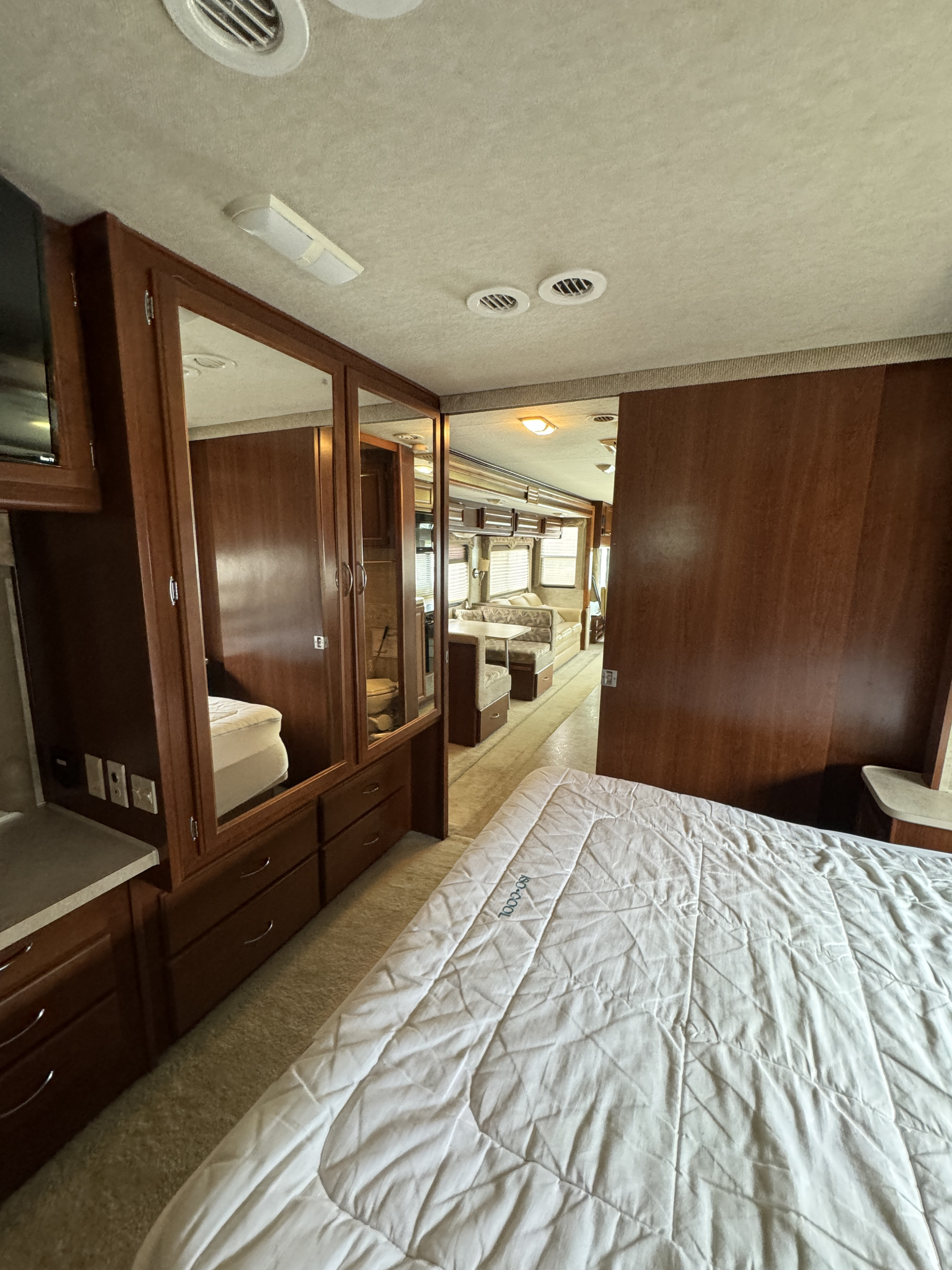 Spacious RV rental interior with bedroom, mirrored cabinetry, and visible living/dining area, perfect for comfort.. Fleetwood Bounder 2007