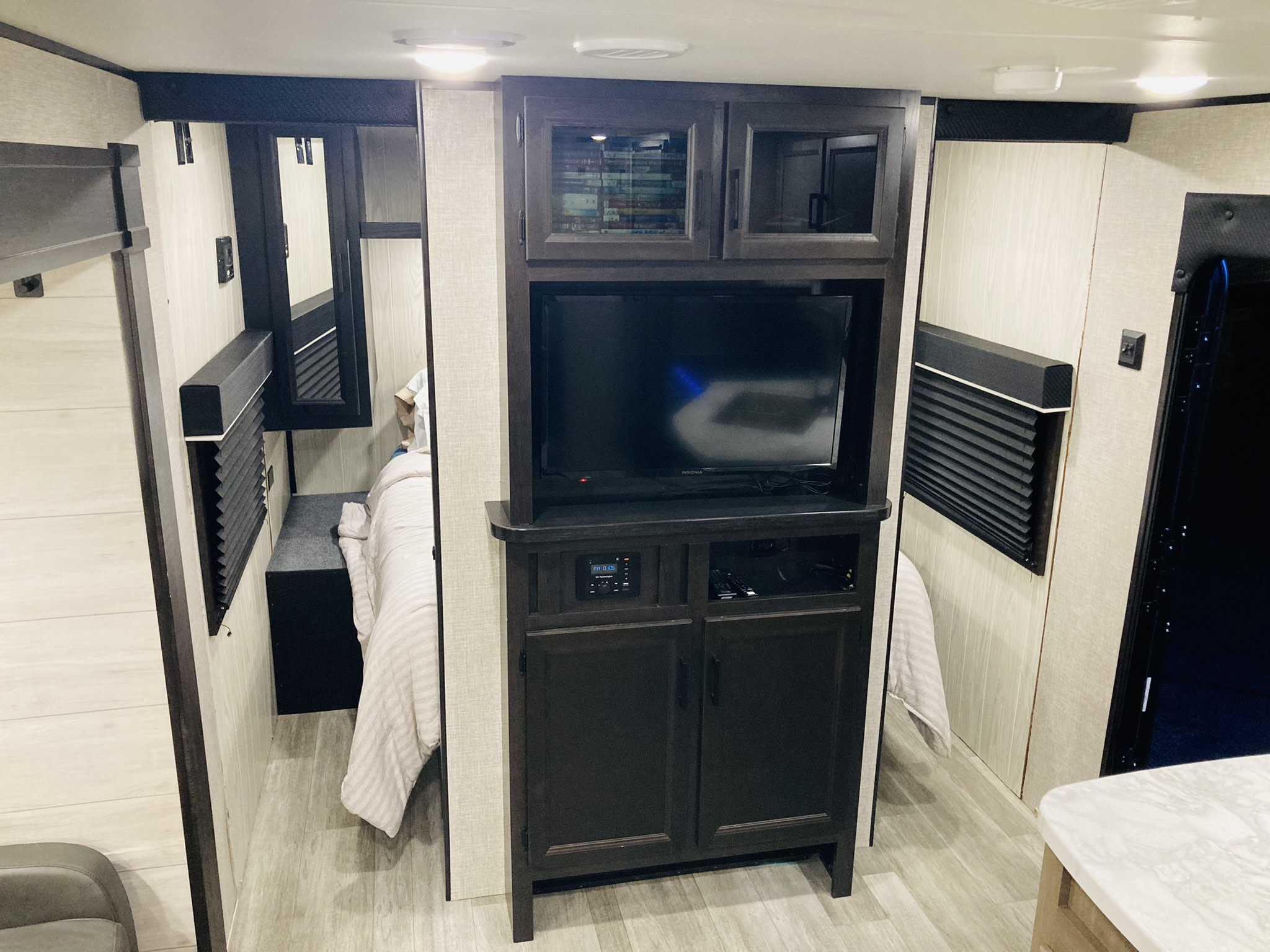 Modern RV rental interior with a bedroom, including a comfortable bed and a central entertainment system for compact living.. Jayco Jay Flight SLX Rocky Mountain Edition 2022