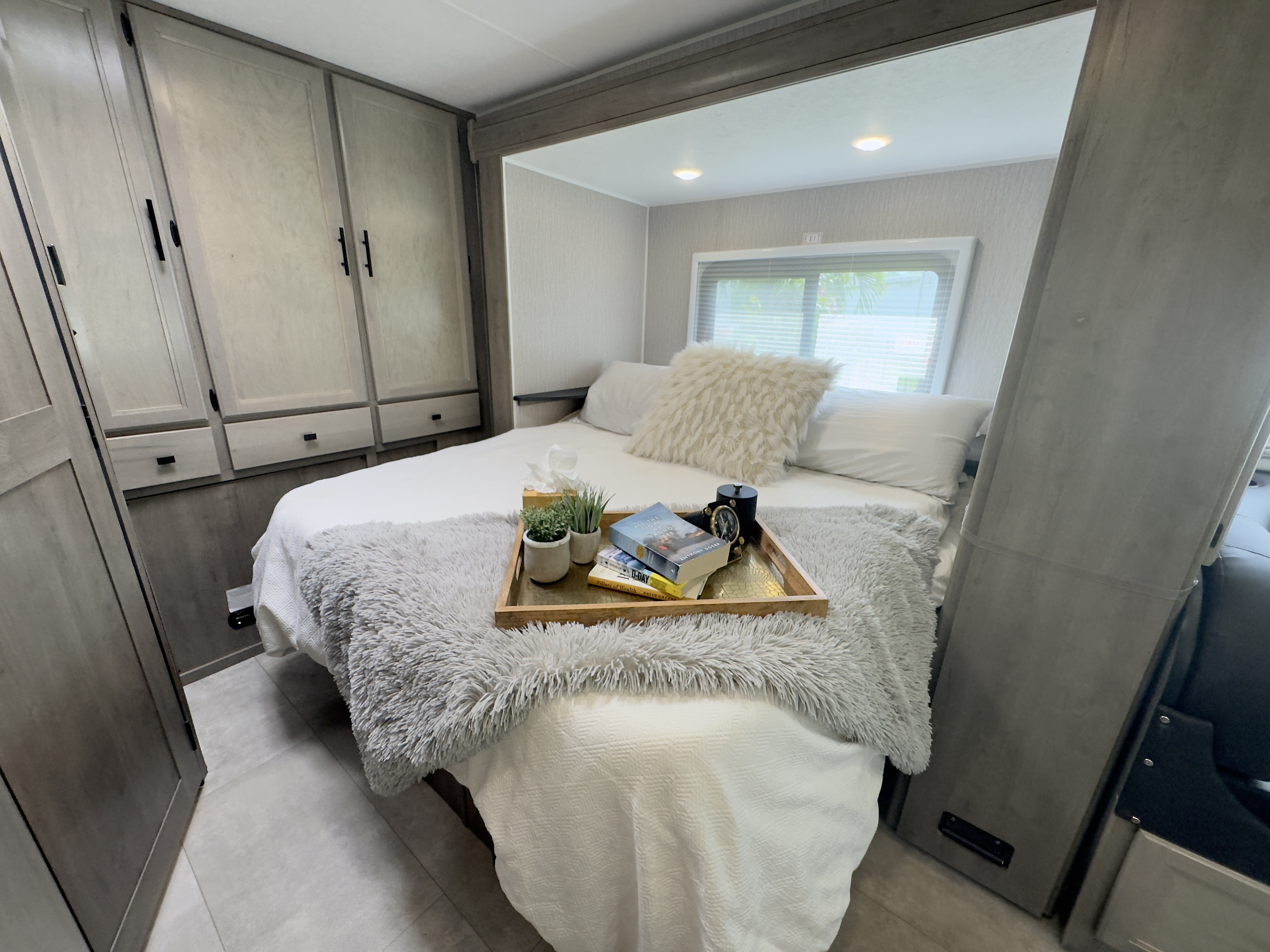 Cozy RV rental bedroom with comfortable bed, overhead cabinets, and a bright window. Ideal for relaxing travel.. Forest River Coachmen Prism Elite 2022