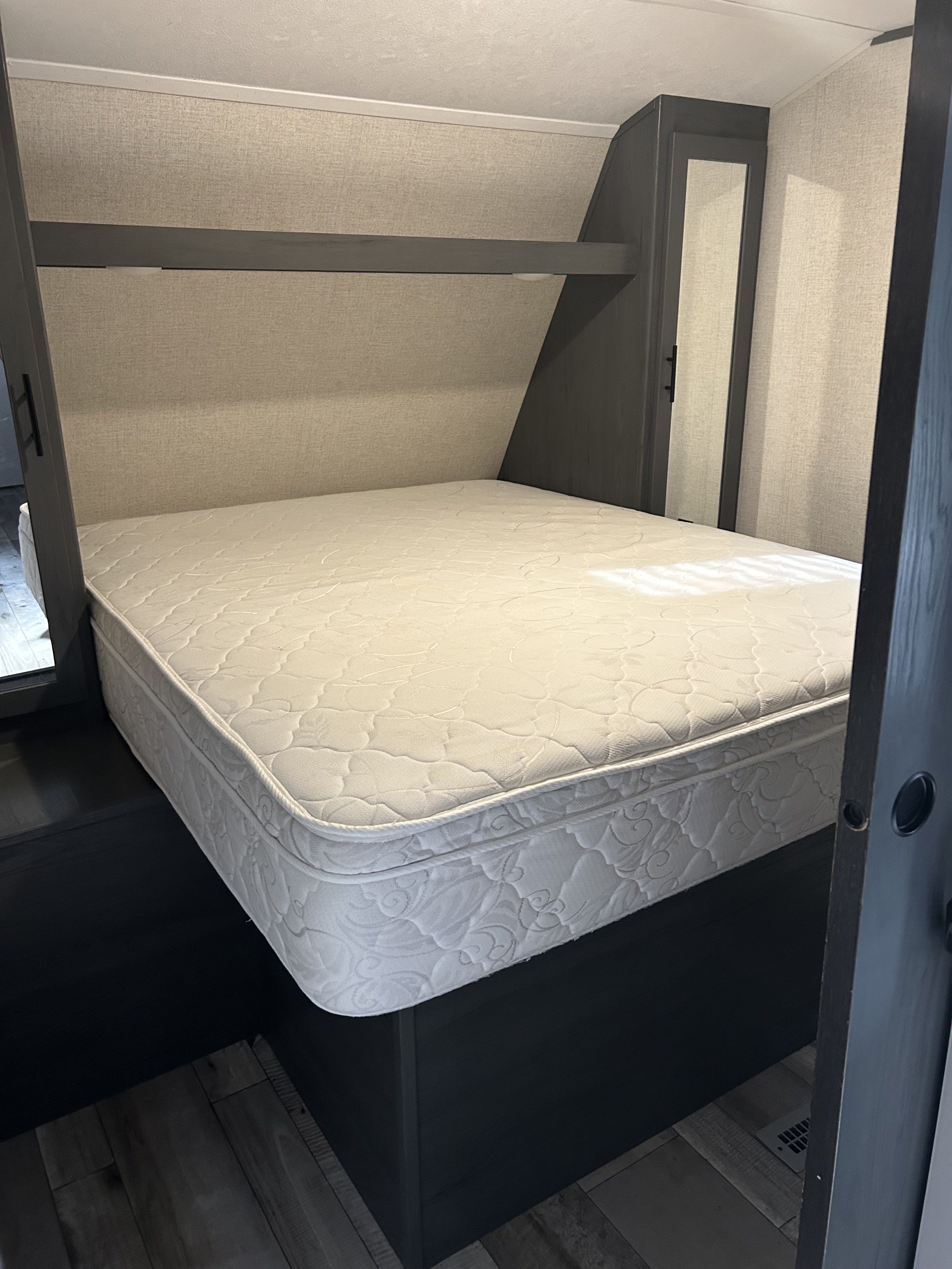 Spacious RV rental bedroom with a comfortable mattress, built-in storage, and modern dark wood accents.. Aspen Trail 3280BHS 2022