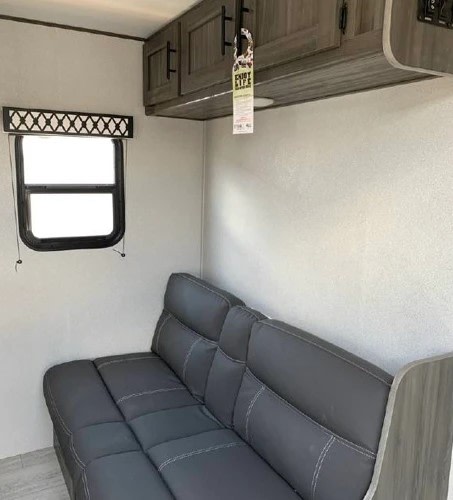 Comfortable gray sofa and overhead cabinets inside an RV rental. Perfect for travel and relaxation.. Shasta Oasis 2021