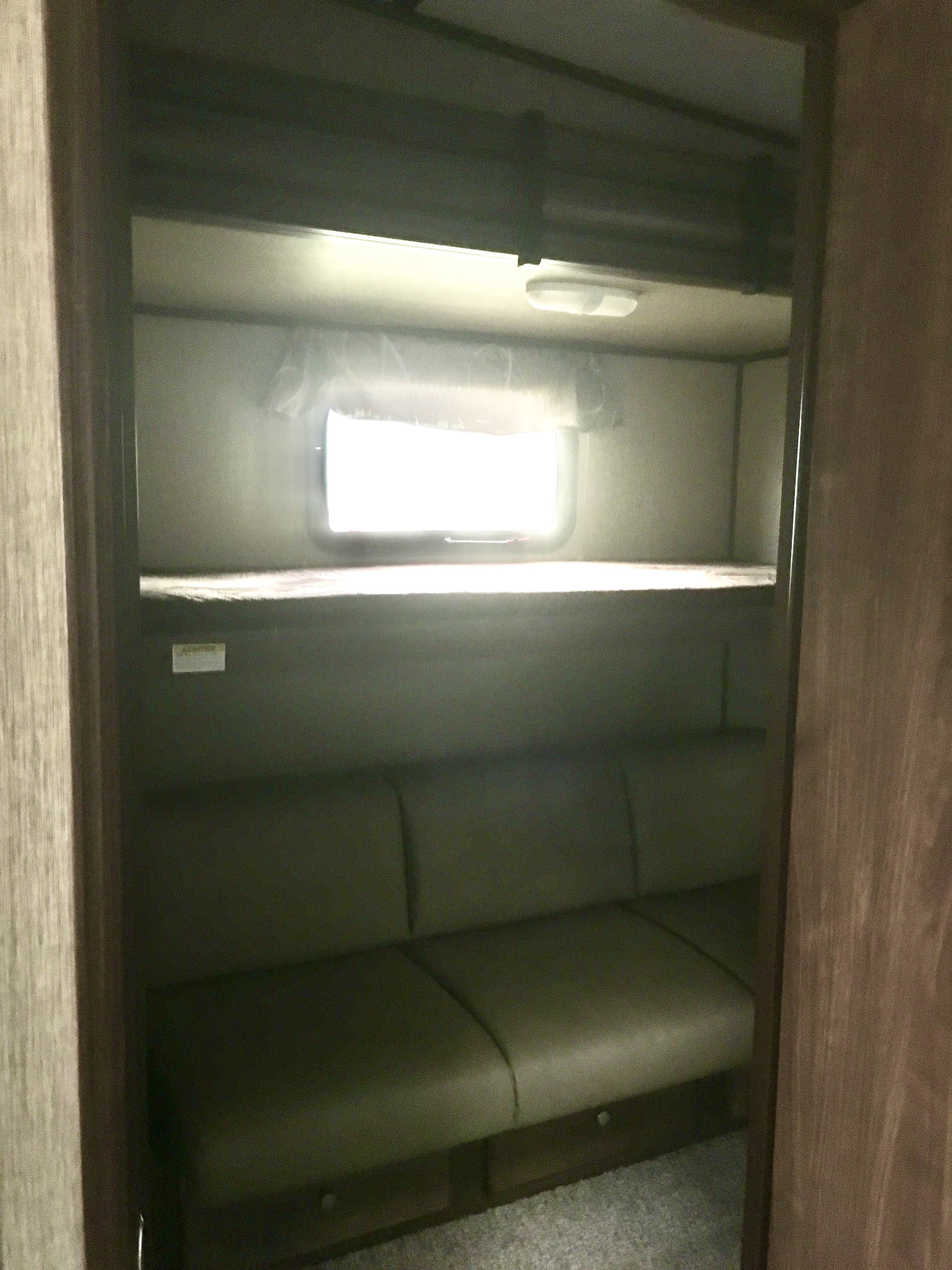 This RV rental offers a cozy interior with a bright window, upper bunk bed, and comfortable lower sofa seating.. Keystone Sprinter 2016