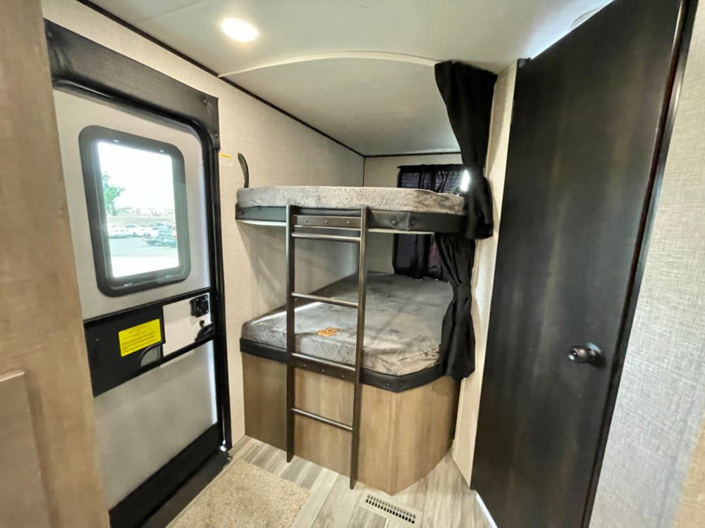 Inside an RV rental, showing a bunk bed area with ladder, the main entry door with a window, and a closed interior door.. JAYCO JAY FLIGHT 286BHSW 2024
