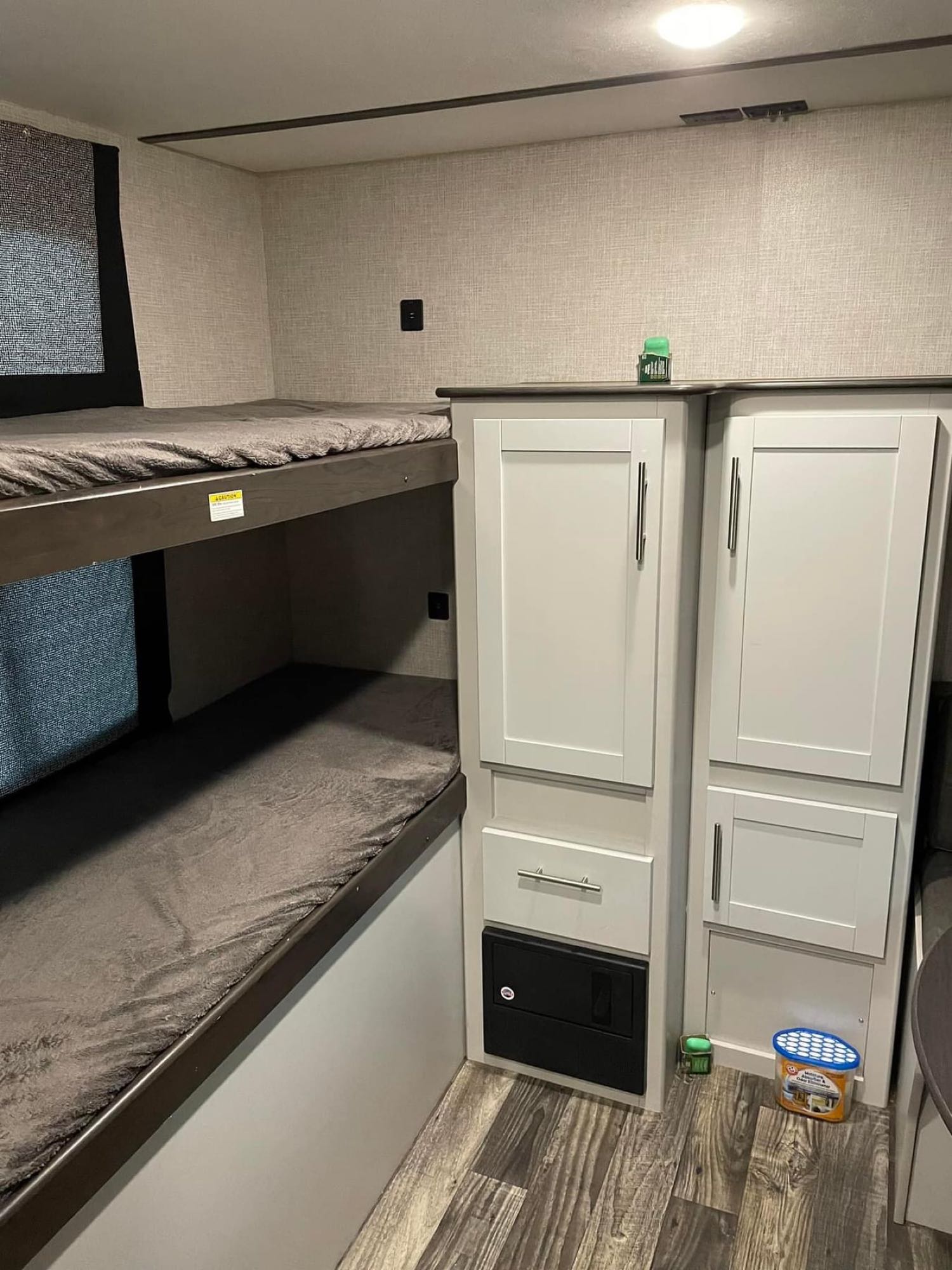 Inside an RV rental: view of comfortable bunk beds, built-in storage cabinets, and wood-look flooring.. Keystone RV Bullet Ultra Lite 2020