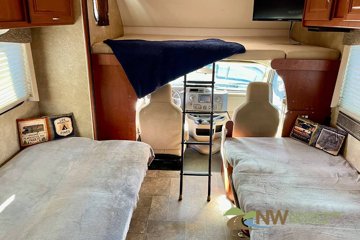 Cozy rv rental interior featuring a comfy bunk over cab, twin beds, and accessible cockpit. Perfect for road trips!. Winnebago Minnie Winnie 2015