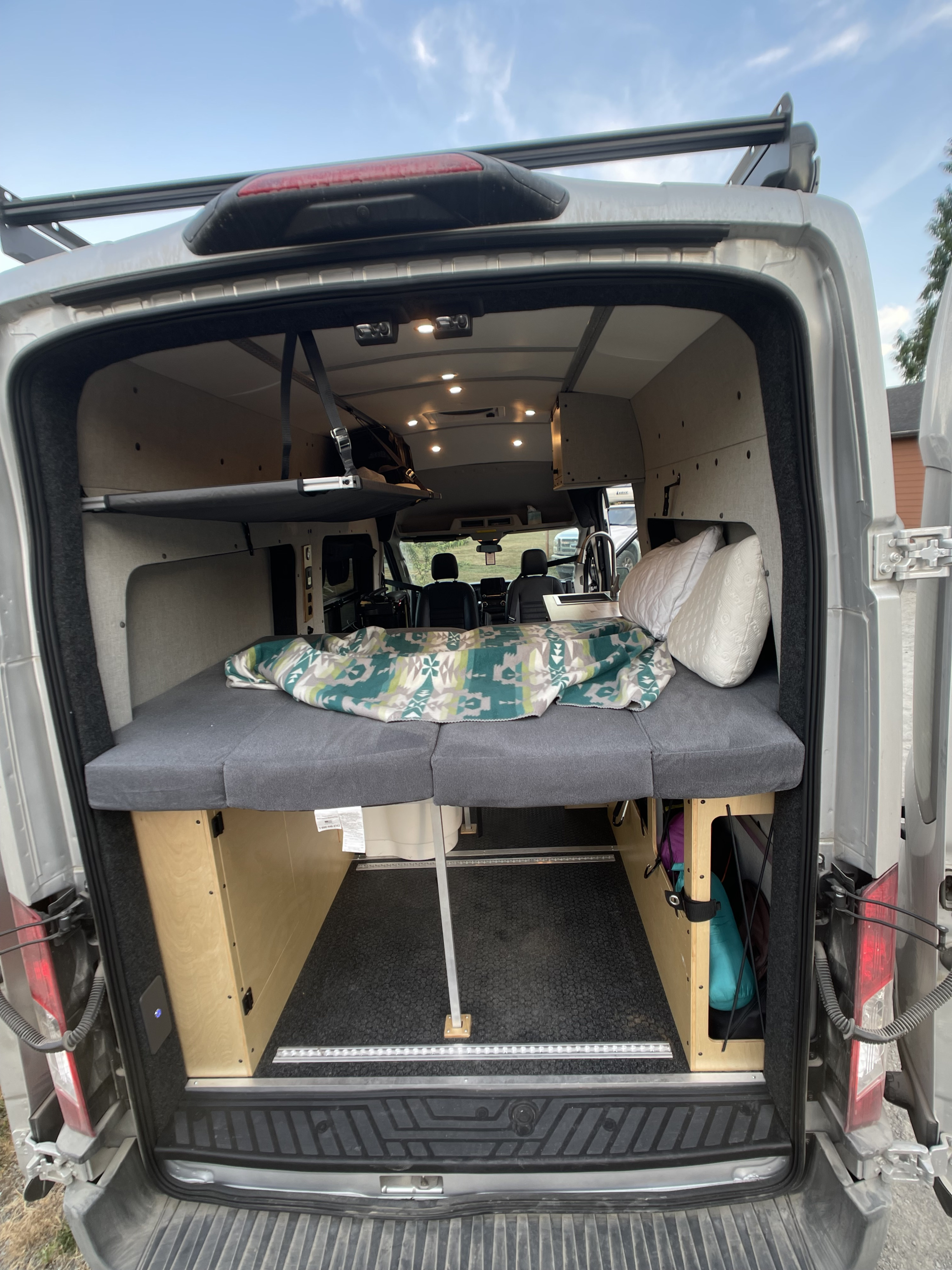 Inside a well-appointed camper van (RV rental) showcasing a bed, storage, and front cabin view.. Ford Transit 350 Ecoboost 2020