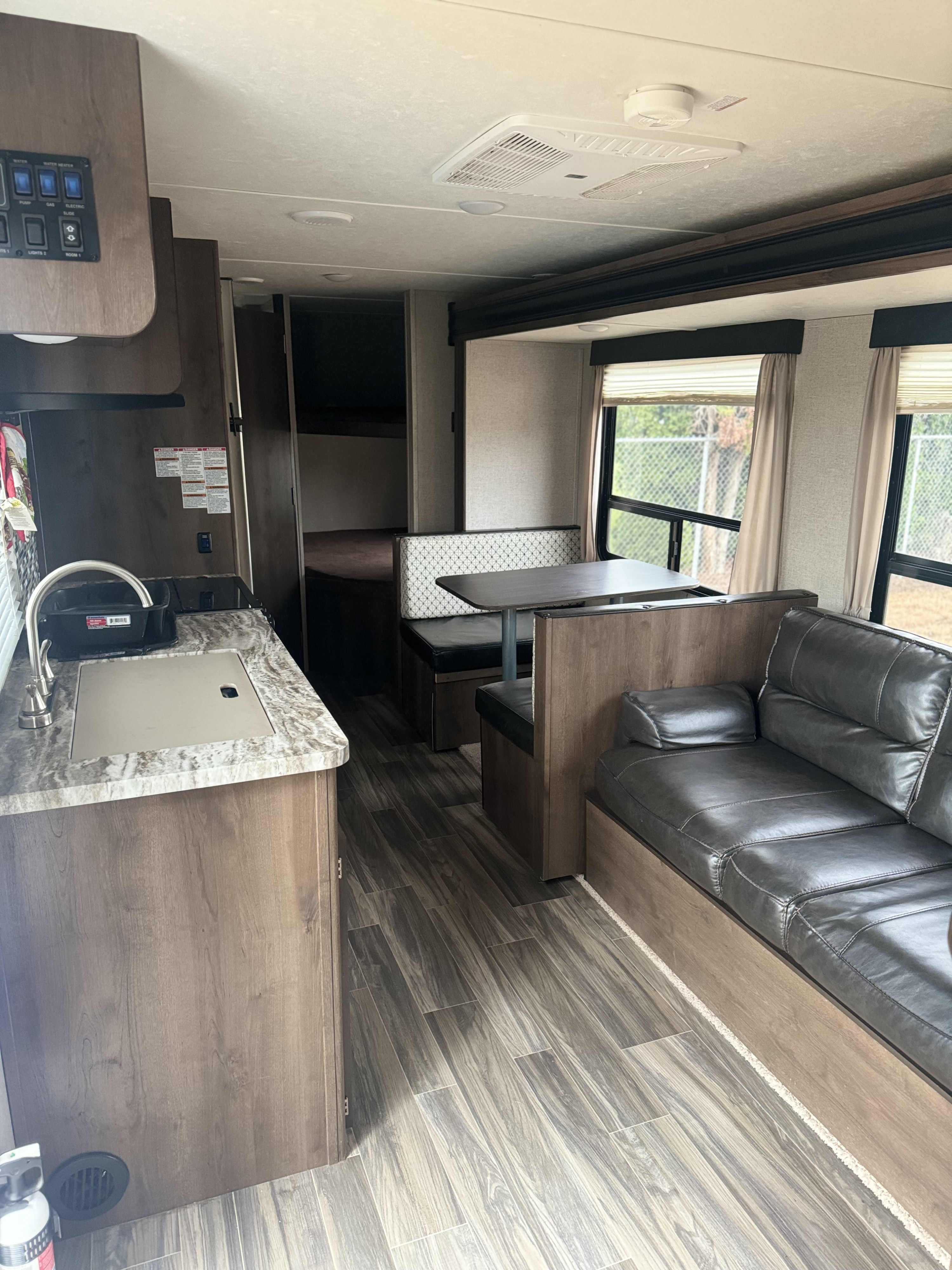 Modern RV rental interior: kitchen, dinette, sofa, and bunk beds. A spacious and clean living space for travel.. Shasta 26db 2020