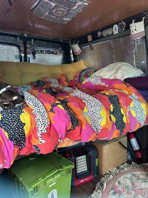 This cozy RV rental setup features a vibrant bed, ample storage, and a portable heater for comfy van life.. Dodge Sprinter Van 2006