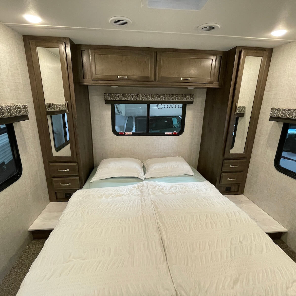 Compact RV rental bedroom featuring a queen bed, built-in storage, and windows.. Gulf Stream Conquest 2022
