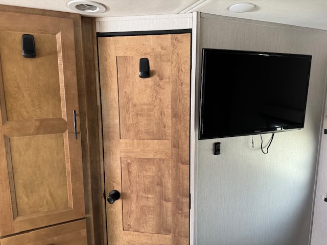 RV rental interior with light wood cabinetry, a door, and a wall-mounted TV.. Forest River Coachmen Prism Elite 2020