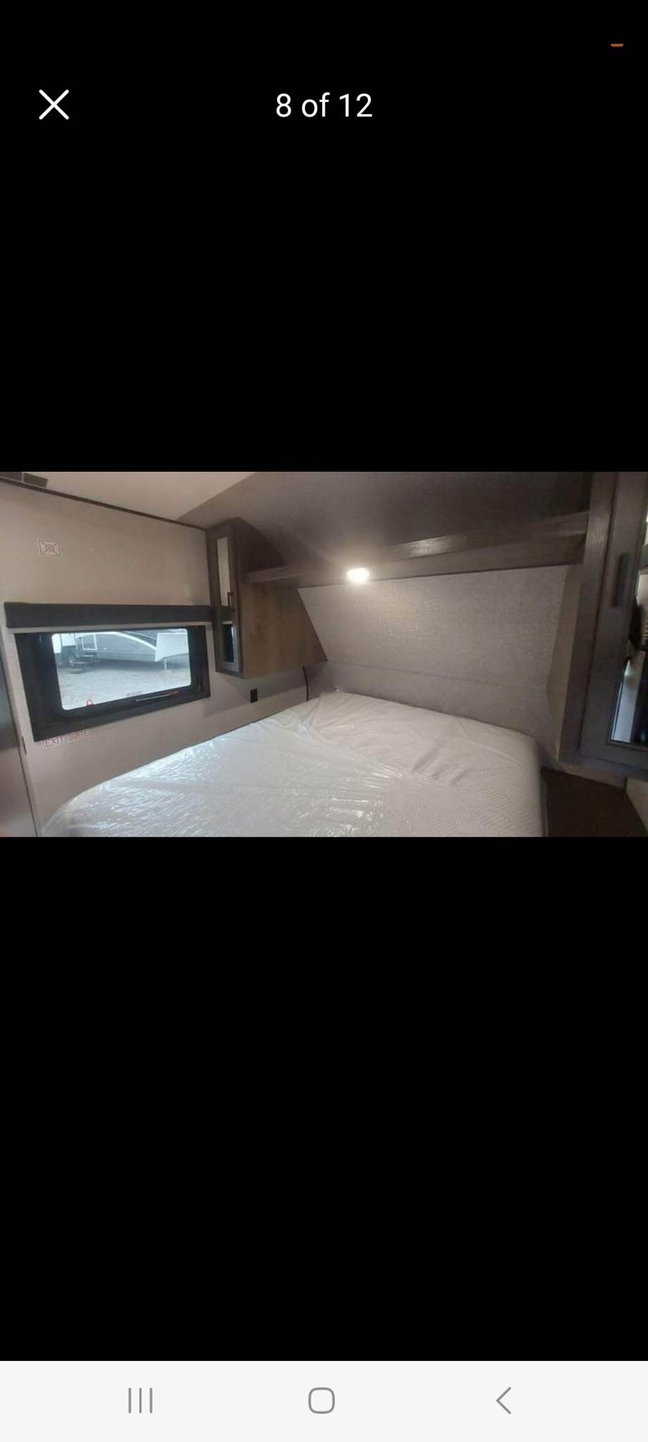 Clean RV rental bedroom featuring a plastic-covered bed, window, and overhead storage.. Highland Ridge RV Open Range 2022