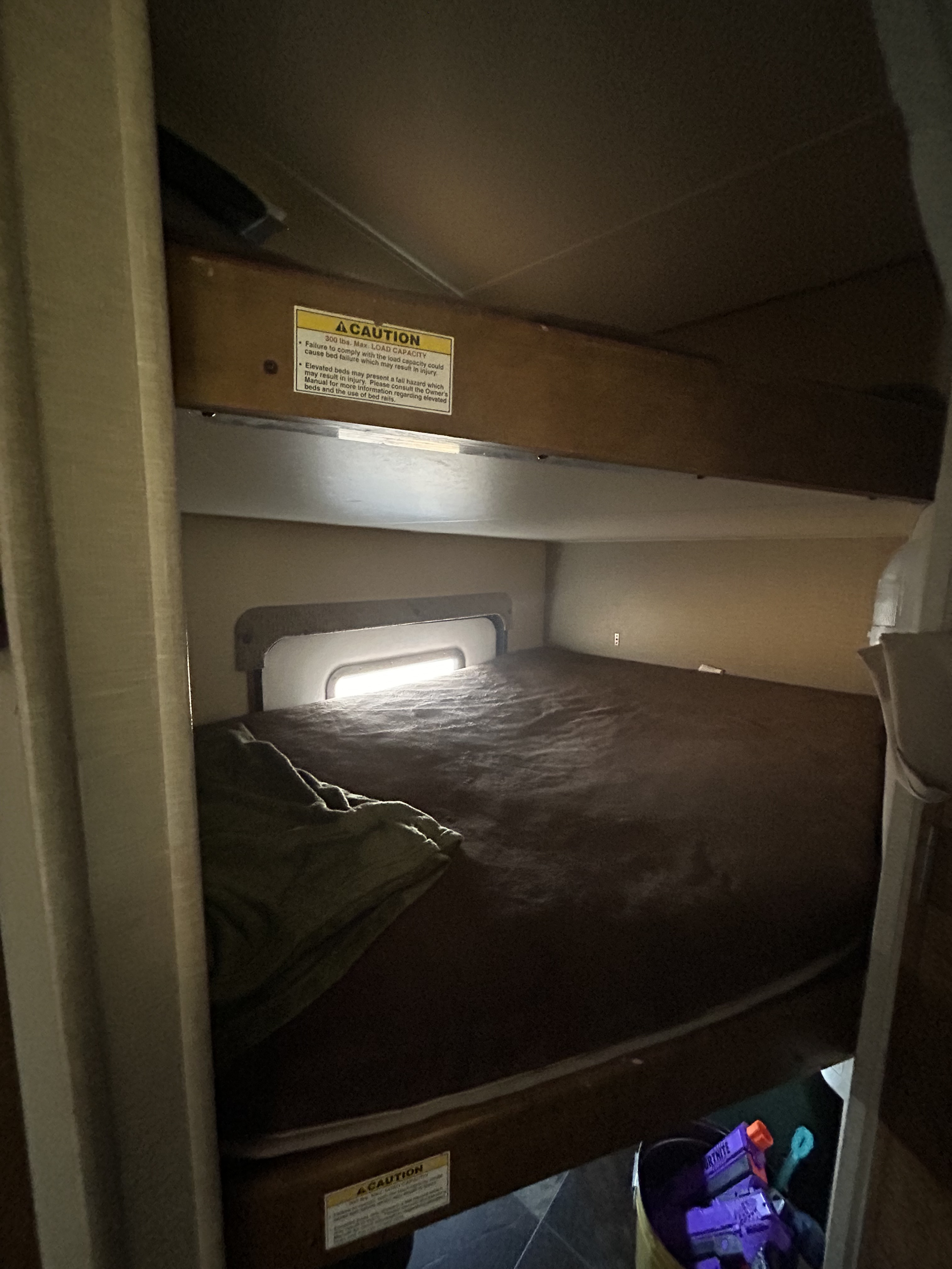Cozy RV rental bunk beds, featuring a lower bed with a window and a top bunk with a 300 lbs max load capacity warning.. Crossroads RV Rezerve 2016