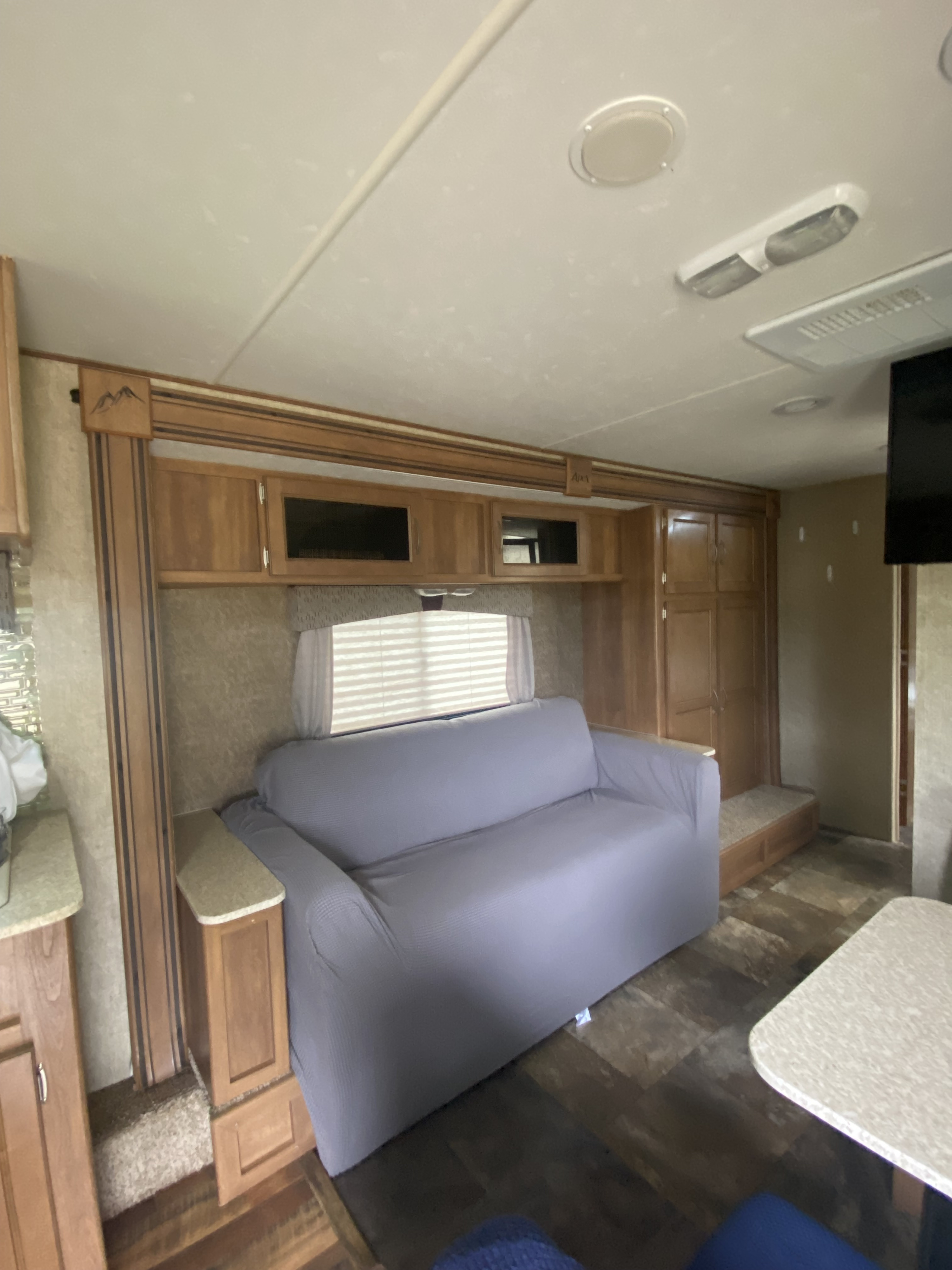 Spacious RV rental interior with a gray sofa, wood cabinets, and plank flooring. Ideal for comfortable travel.. Coachmen Apex 2014