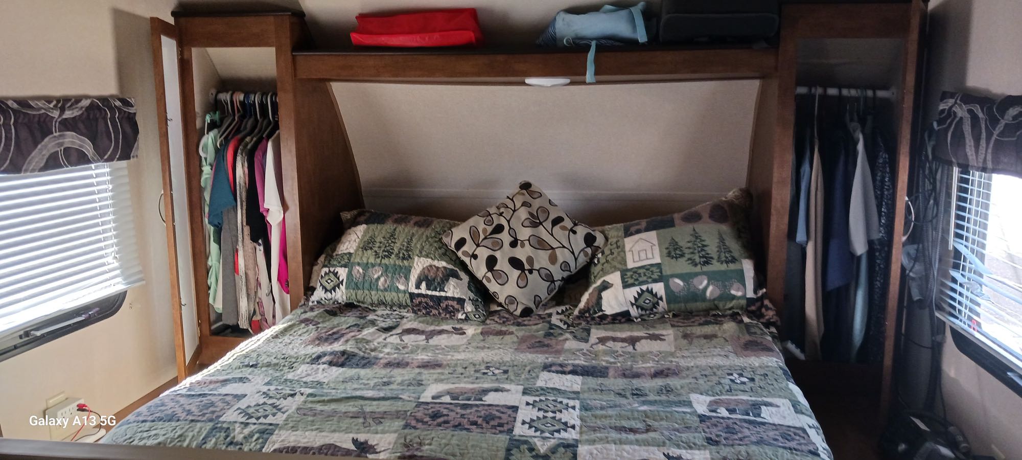 Inside an RV rental, a cozy bedroom features a nature-themed quilt, ample storage wardrobes, and window blinds.. Forest River Salem Cruise Lite 2018