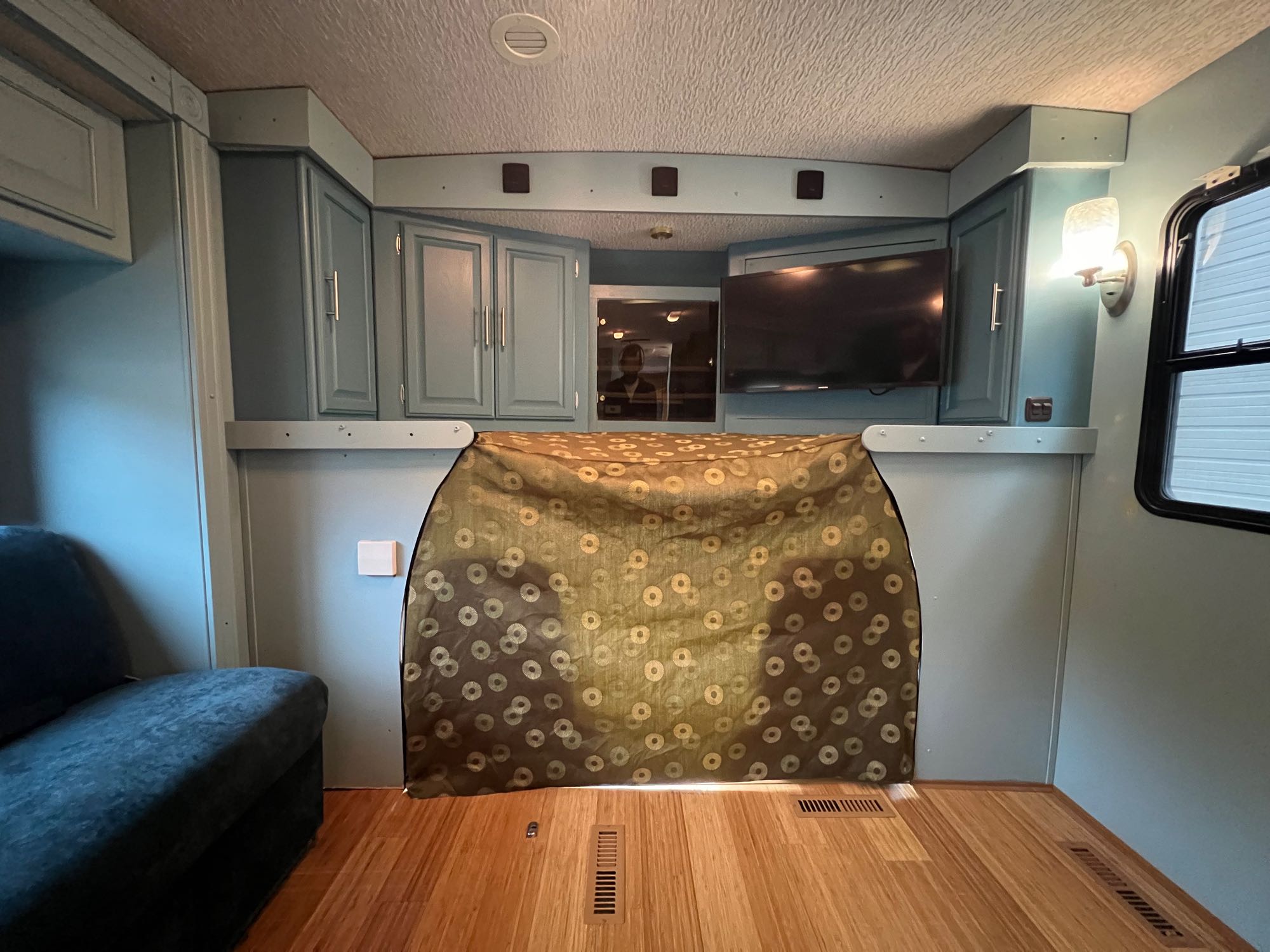 Inside a well-appointed RV rental: blue cabinetry, flat-screen TV, and sofa. Modern mobile living space with wood floors.. Winnebago Minnie Winnie 2003
