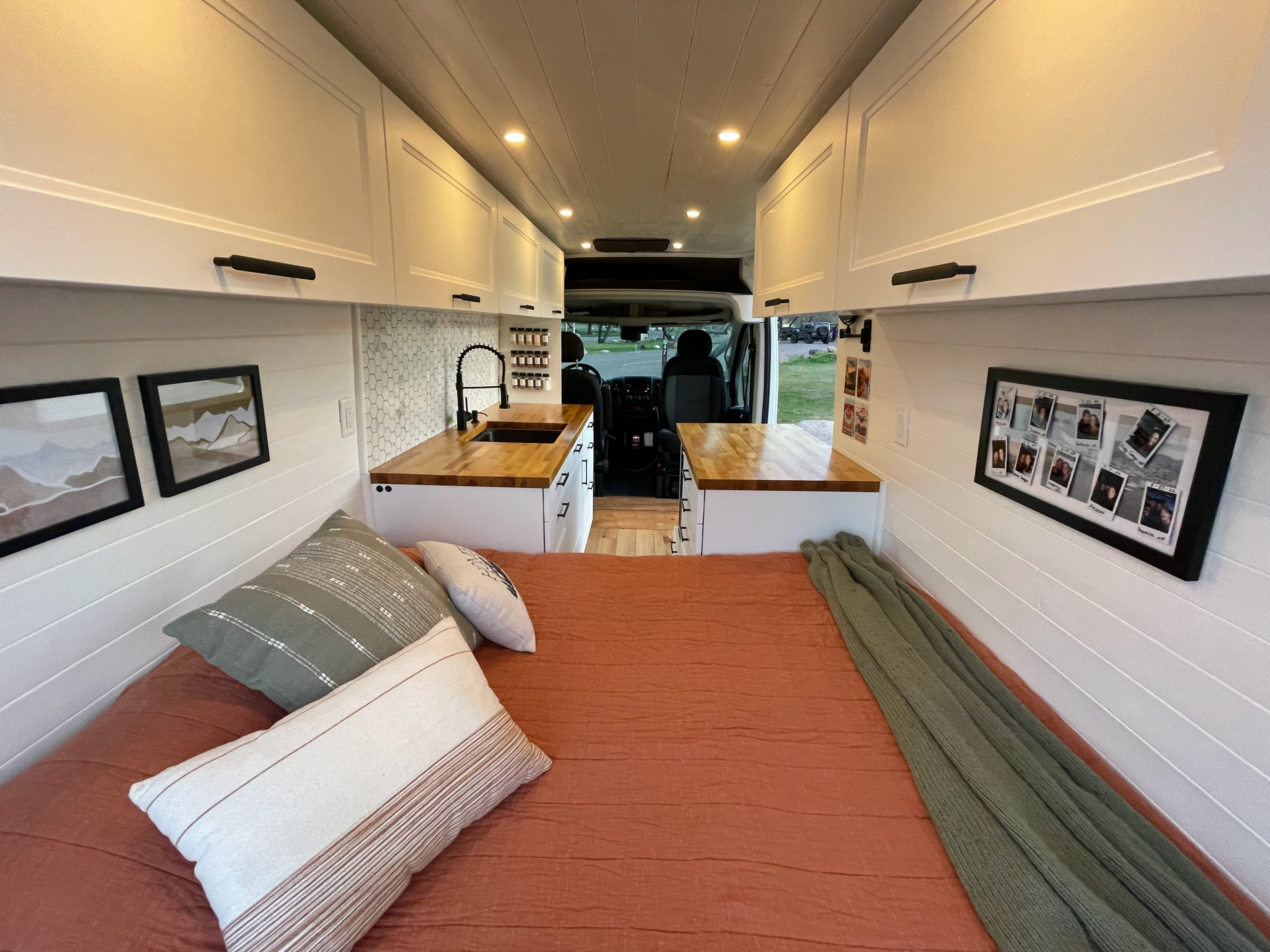 Cozy RV rental interior featuring a bed, kitchen, overhead cabinets, and stylish decor for mobile living.. Dodge Ram ProMaster 2500 2021