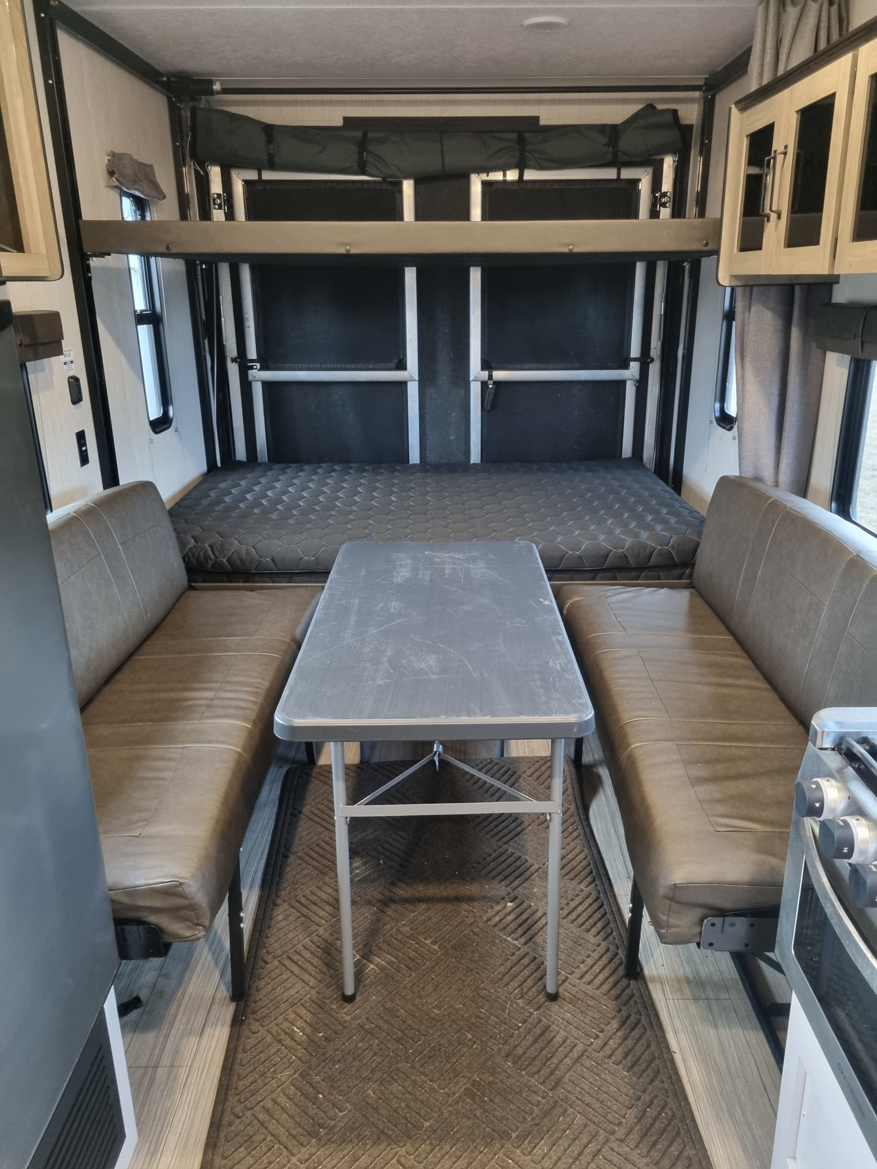 RV rental interior with a cozy dinette (benches & table) and a versatile power lift bed system in the rear.. Palomino Puma 2022