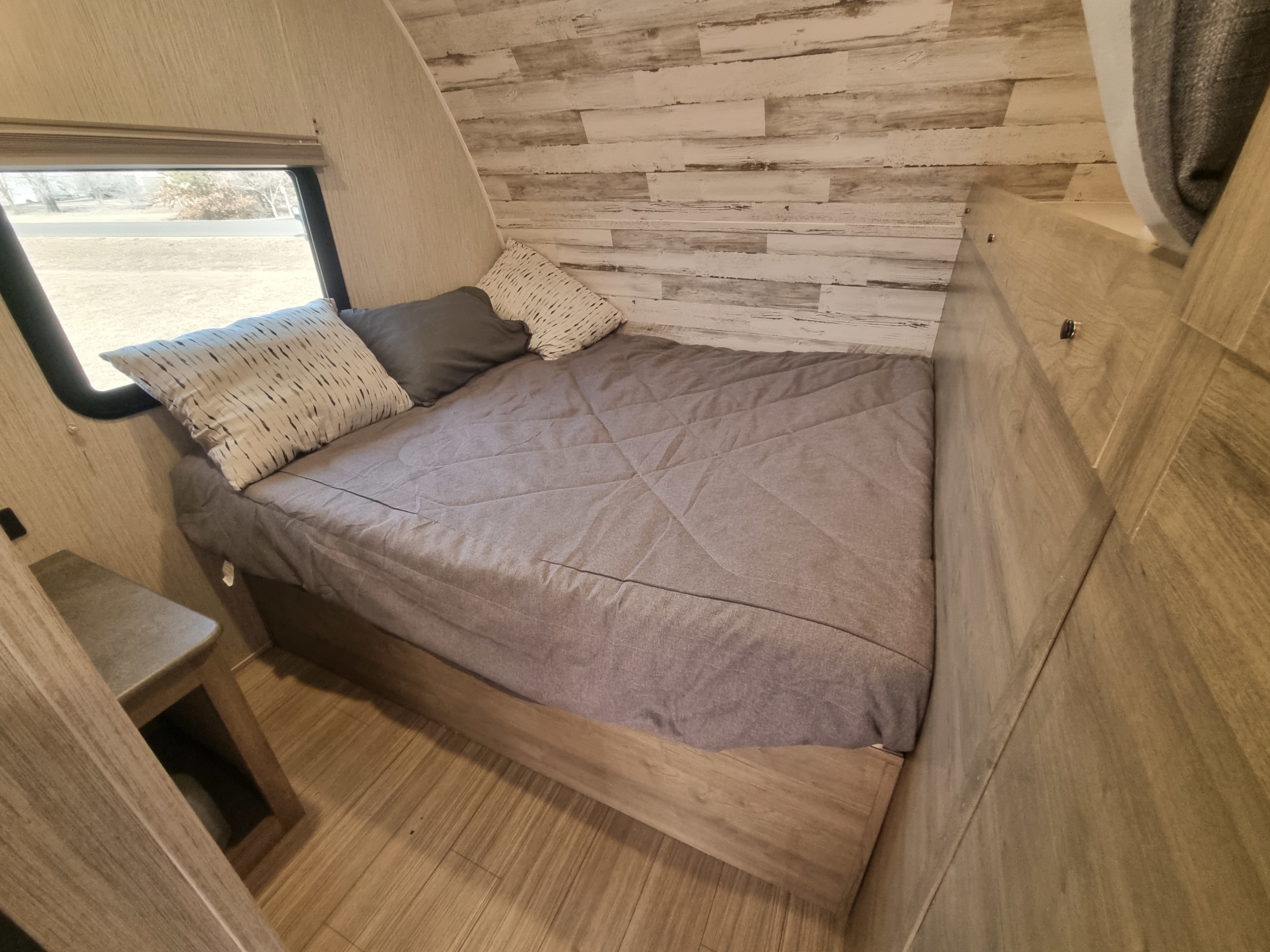 Comfortable RV rental bedroom with gray bedding, wood walls, and a scenic window view.. Palomino Puma 2022