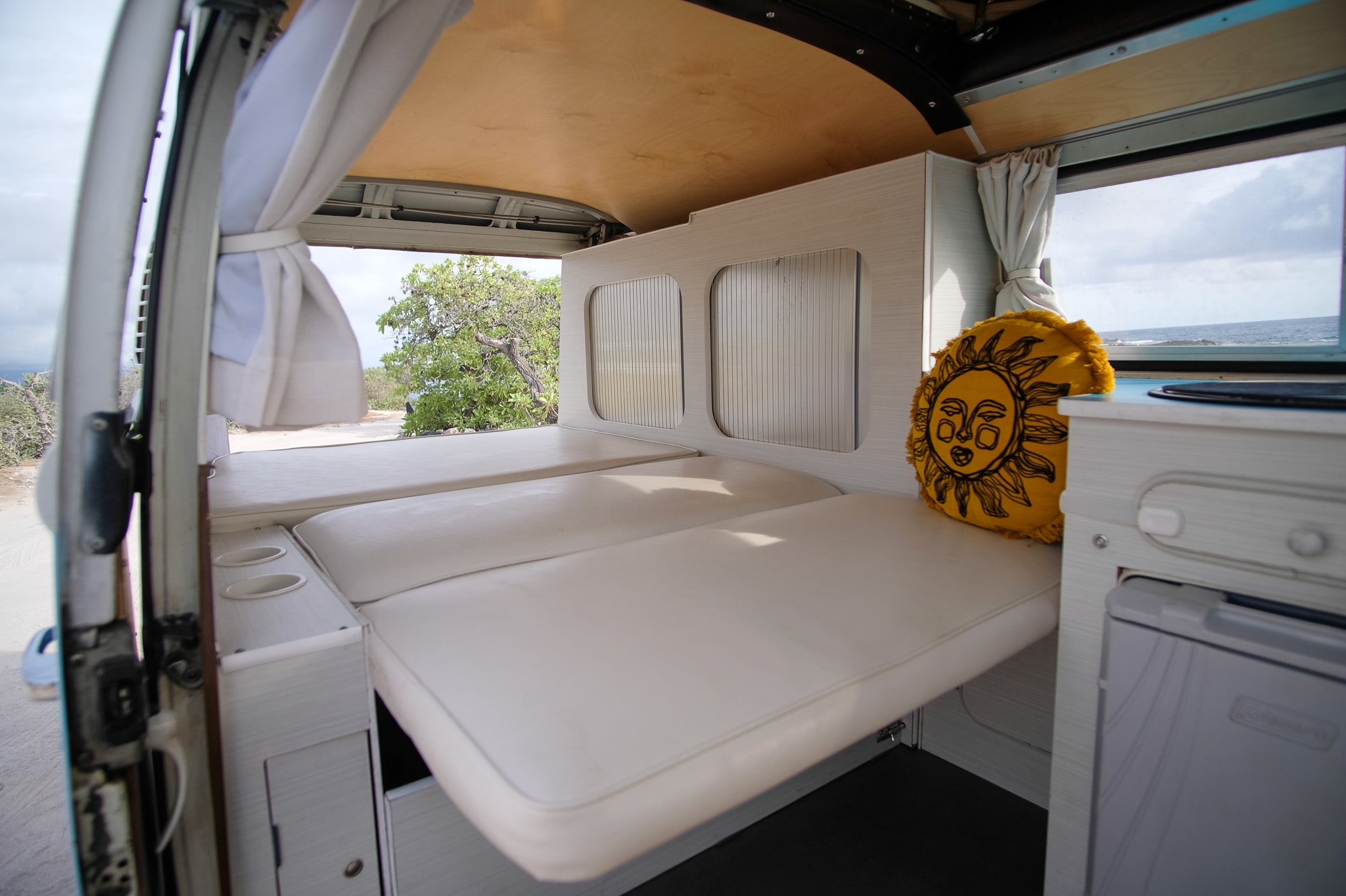 Bright rv rental interior featuring a custom bed, built-in storage, and an ocean view from the window.. Volkswagen T2 Westfalia 1976