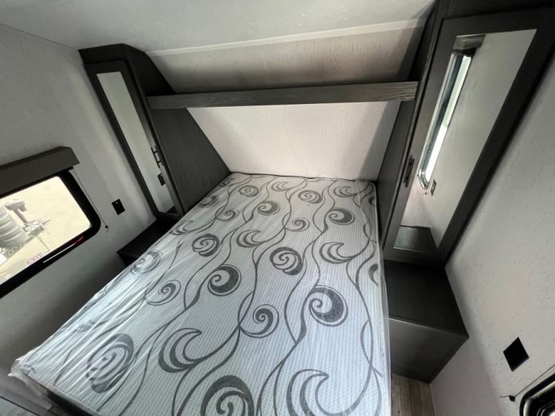 Clean and comfortable RV rental bedroom featuring a patterned mattress and convenient built-in storage.. Dutchman 26BHCWE 2024