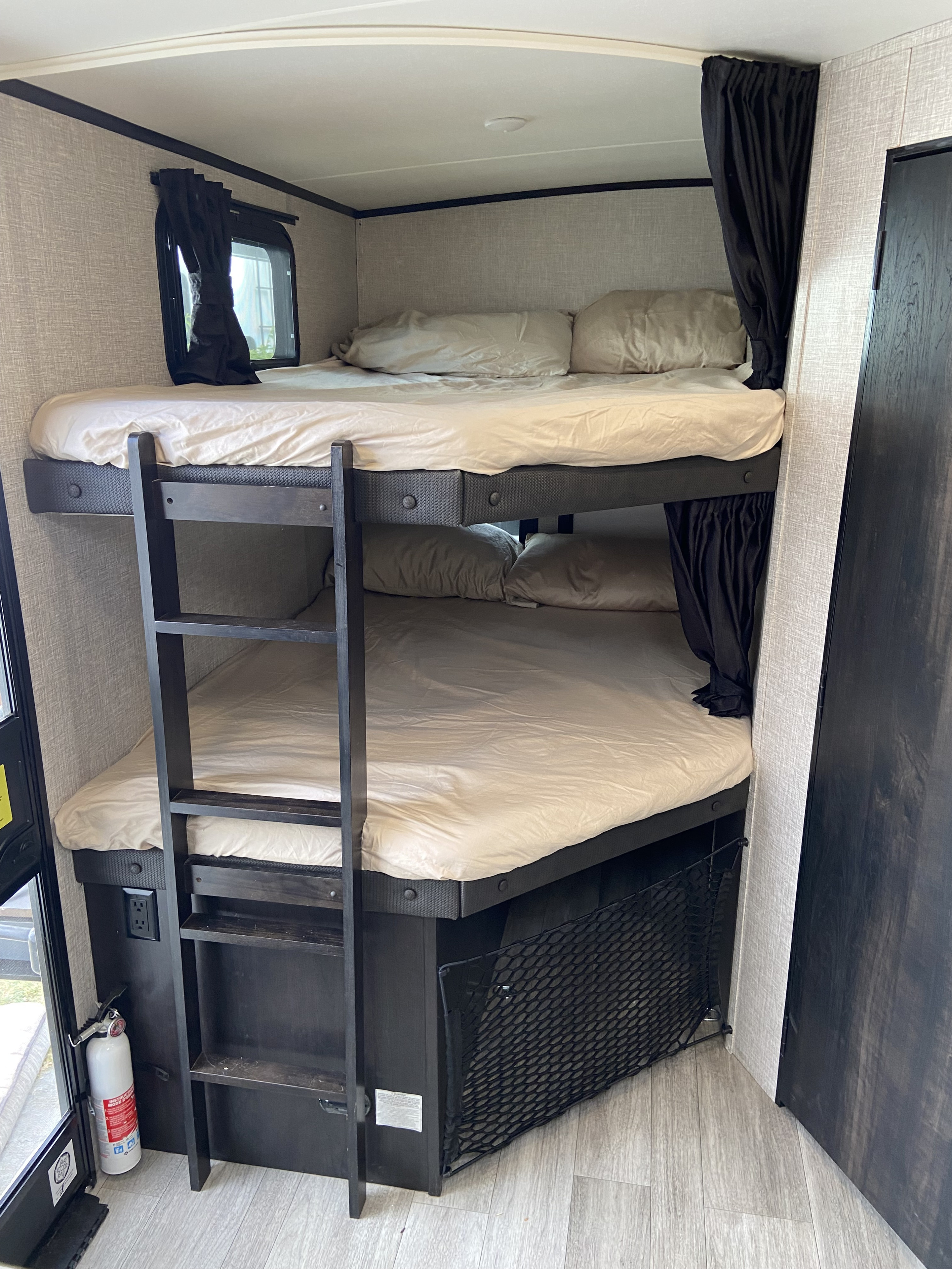 Cozy RV rental interior with spacious bunk beds, ladder, privacy curtains, and fire extinguisher for safe travels.. Jayco White Hawk 2023