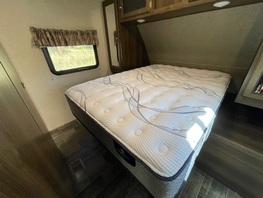 Spacious RV rental bedroom with a comfy mattress, ideal for travel. Enjoy a cozy night on the road.. Keystone Bullet Ultra 2018