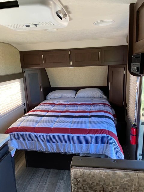 Comfortable RV rental bedroom featuring a striped comforter, overhead storage, and AC. Perfect for a camper trip.. Forest River Cherokee Wolf Pup Cascade 2017