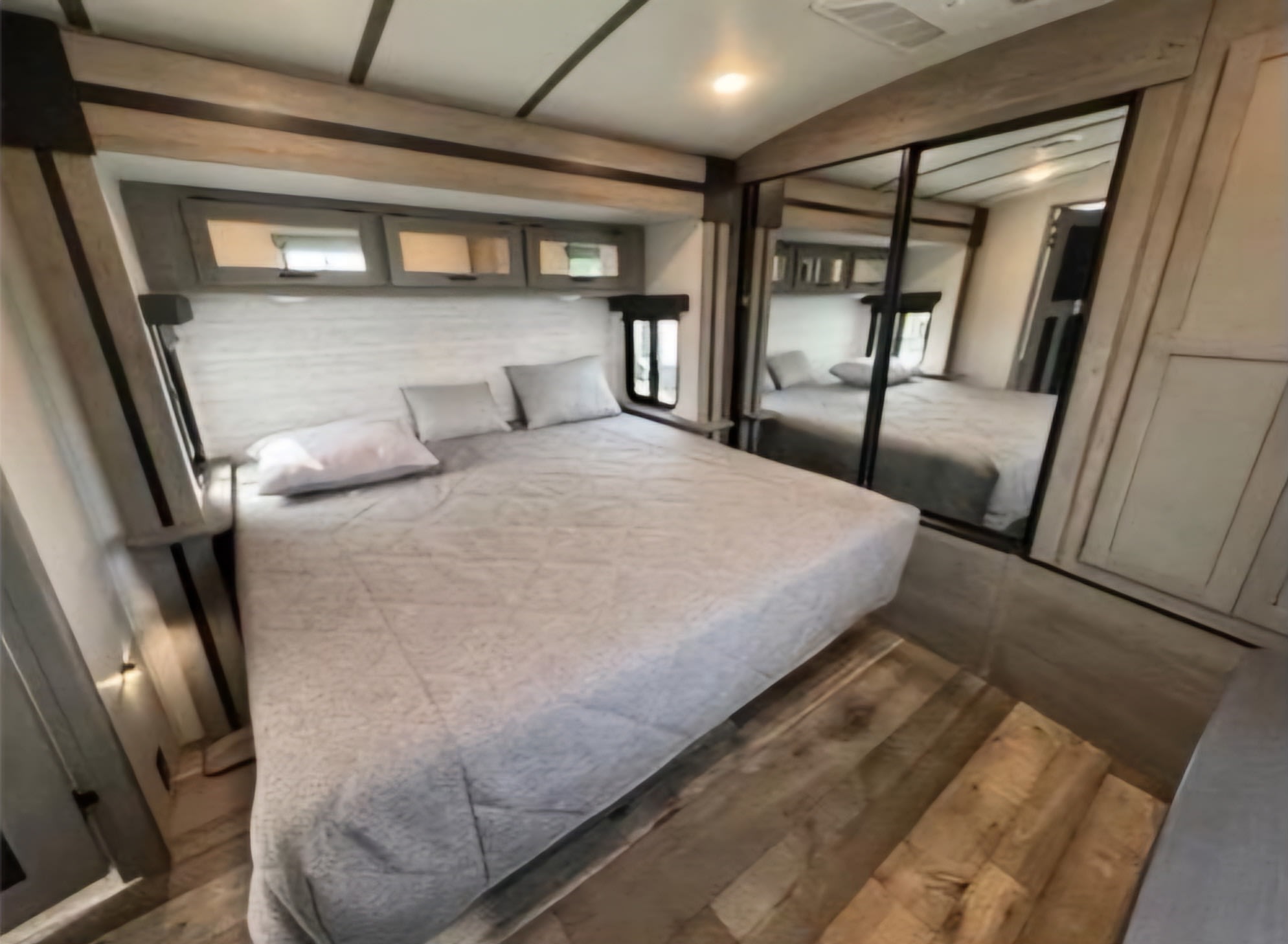 Spacious RV rental bedroom with comfortable queen bed, mirrored closet, and overhead storage, perfect for travel.. Keystone RV Outback 2021