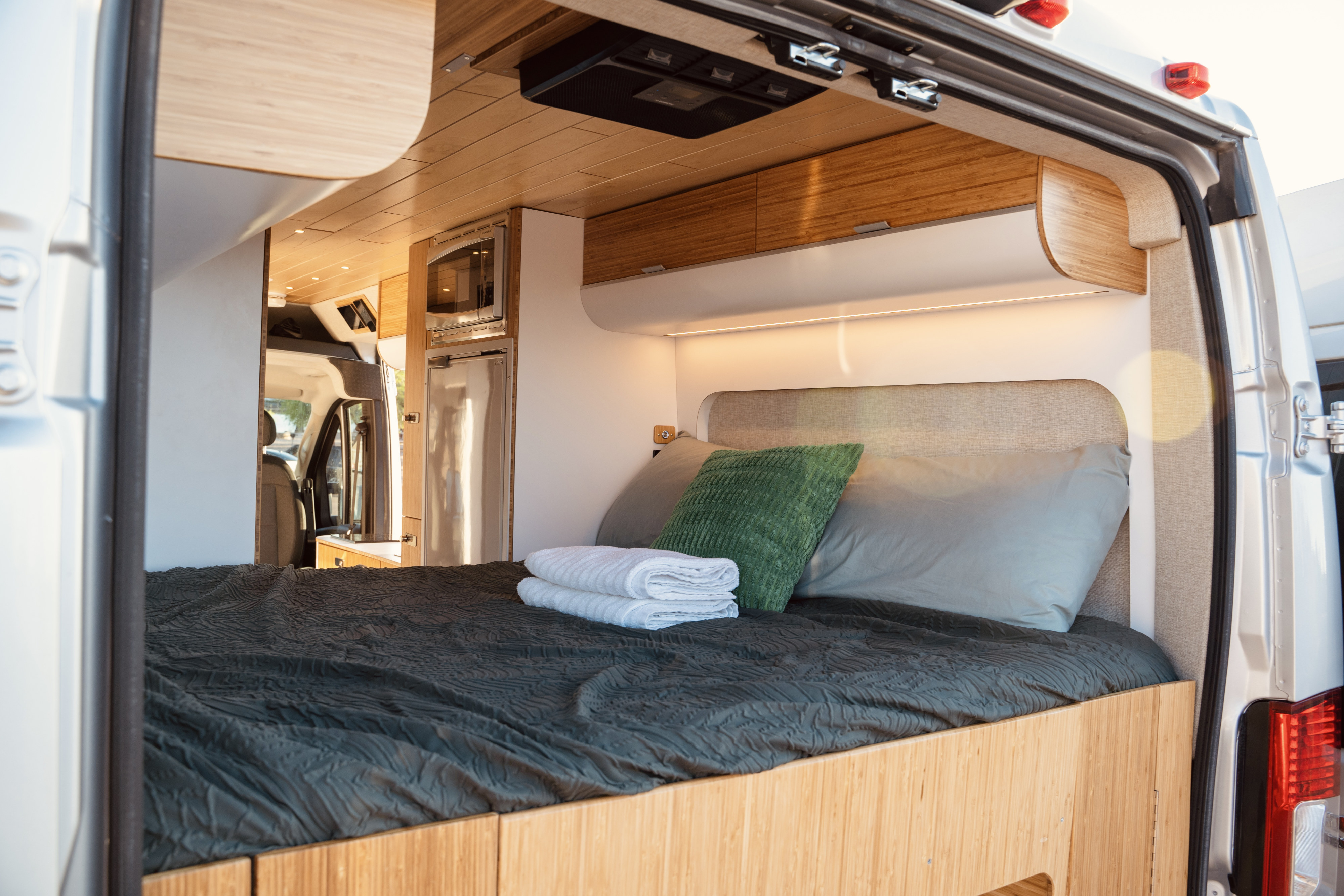 Modern rv rental interior: inviting bed, bamboo cabinetry, & integrated kitchen appliances. Ready for adventure!. Noovo Lite 2023