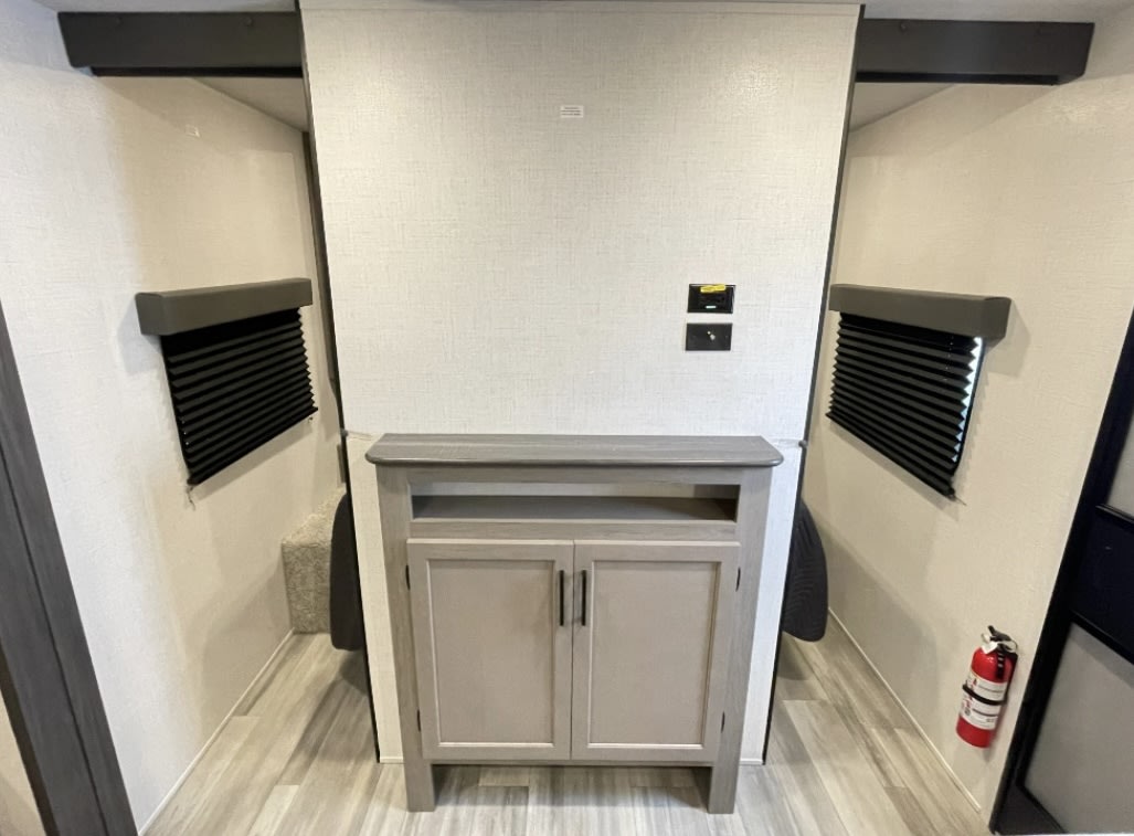 RV rental interior: Cozy bedroom with bunk beds, central cabinet, window blinds, and a fire extinguisher.. Keystone RV HIDEOUT 31BRD 2024
