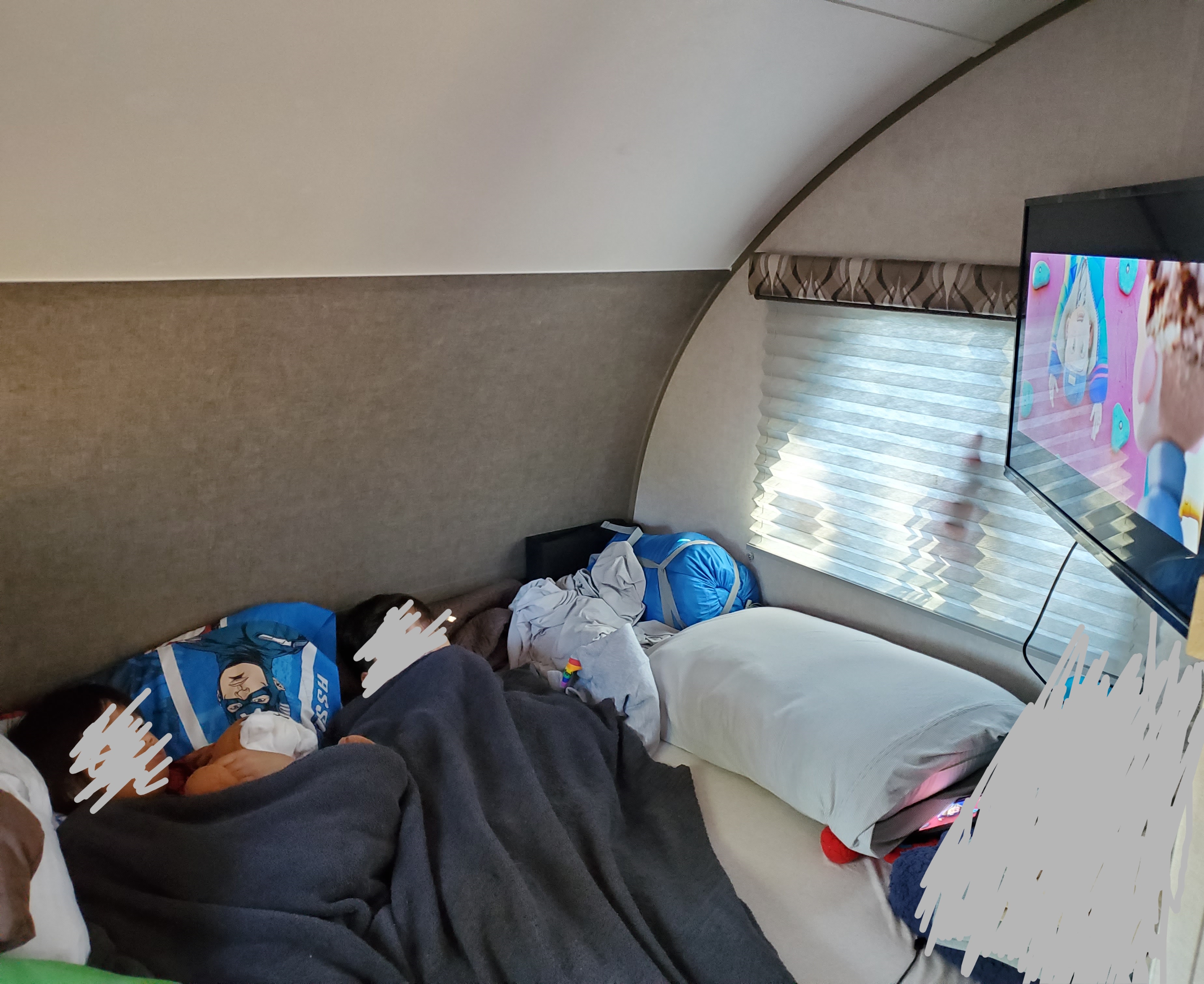 Cozy RV rental interior with two people resting in bed, one on a Captain America pillow, watching TV.. R-Pod R-Pod Trailer 2019