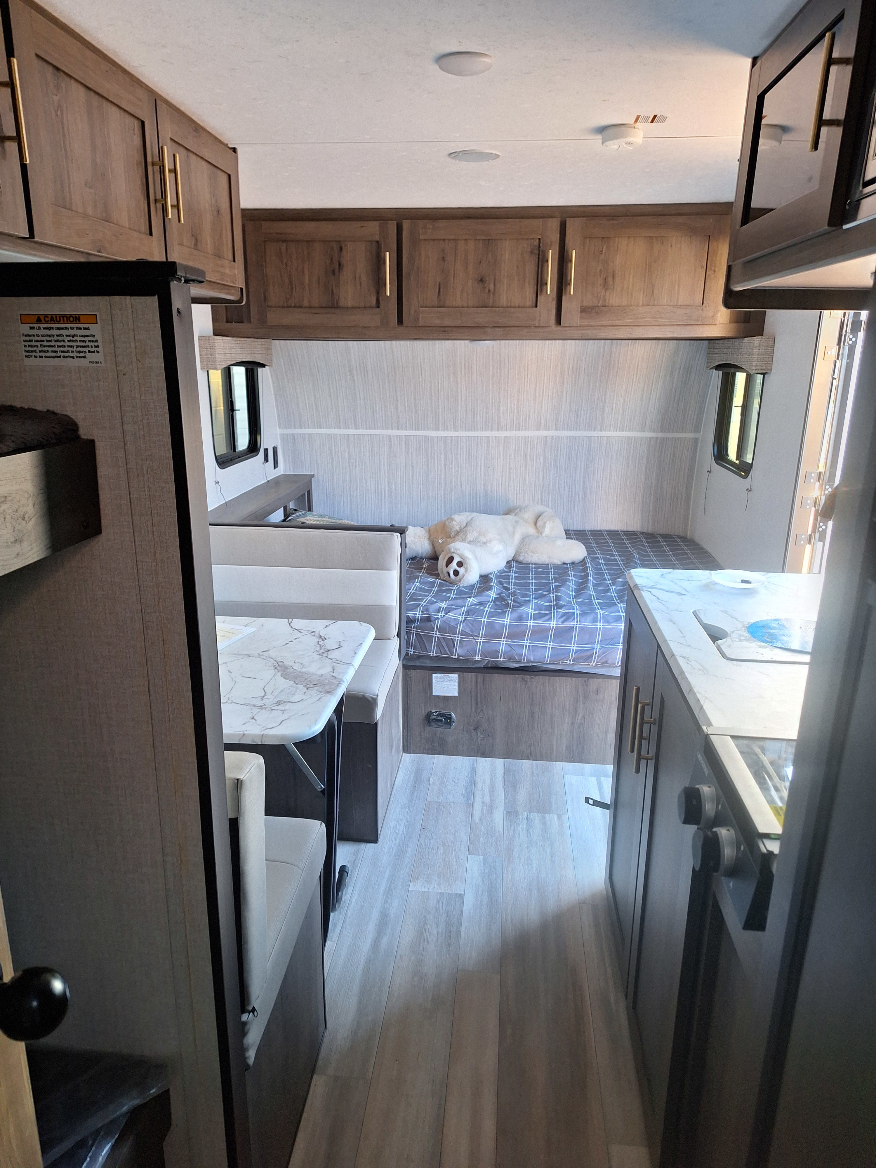 Cozy rv rental interior featuring a dog sleeping on the bed, a dining booth, and a compact kitchen area.. Forest River Viking 2022