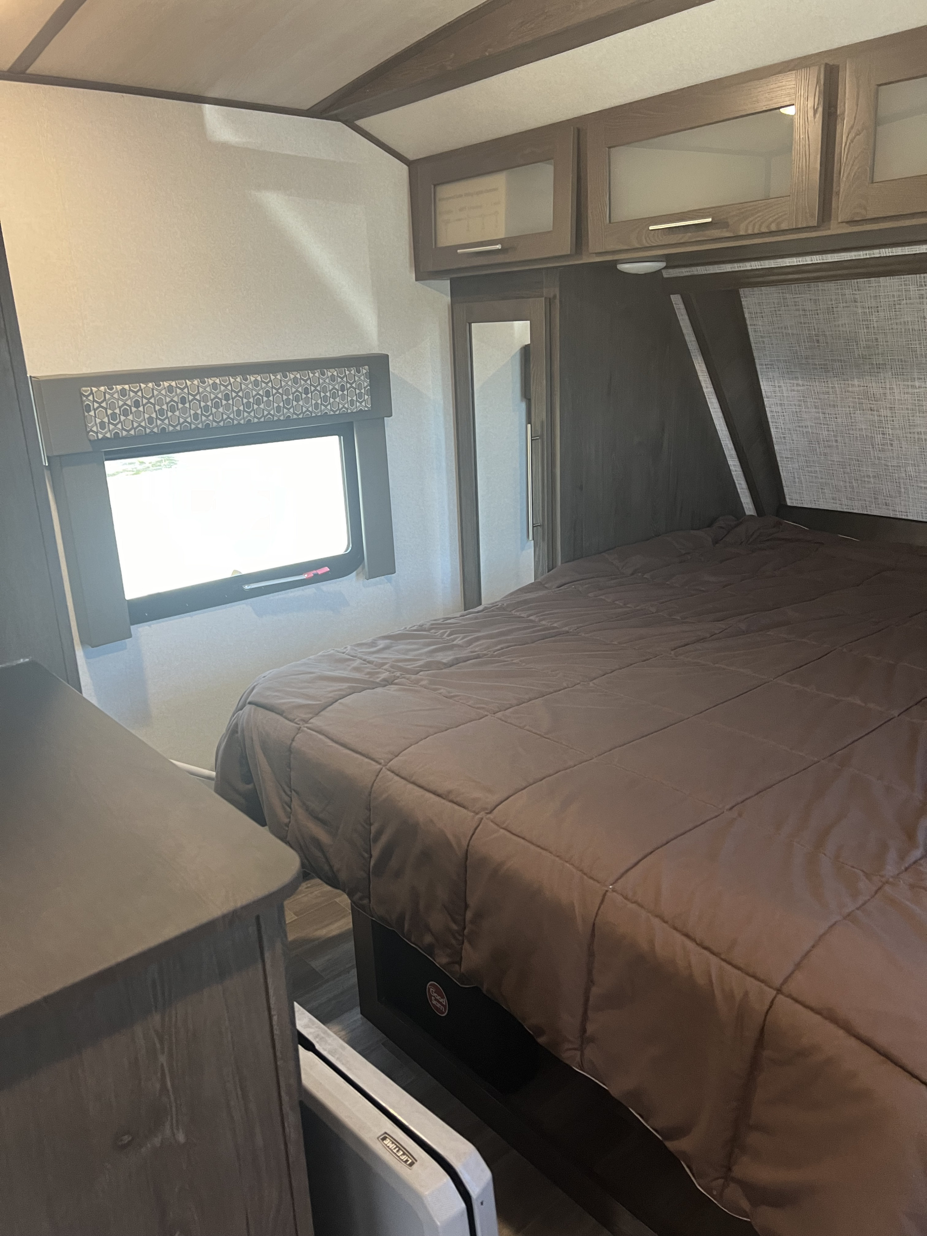 An inviting RV rental bedroom with a comfortable bed, overhead storage, and a window, perfect for your next adventure.. Forest River Salem Hemisphere GLX 2019