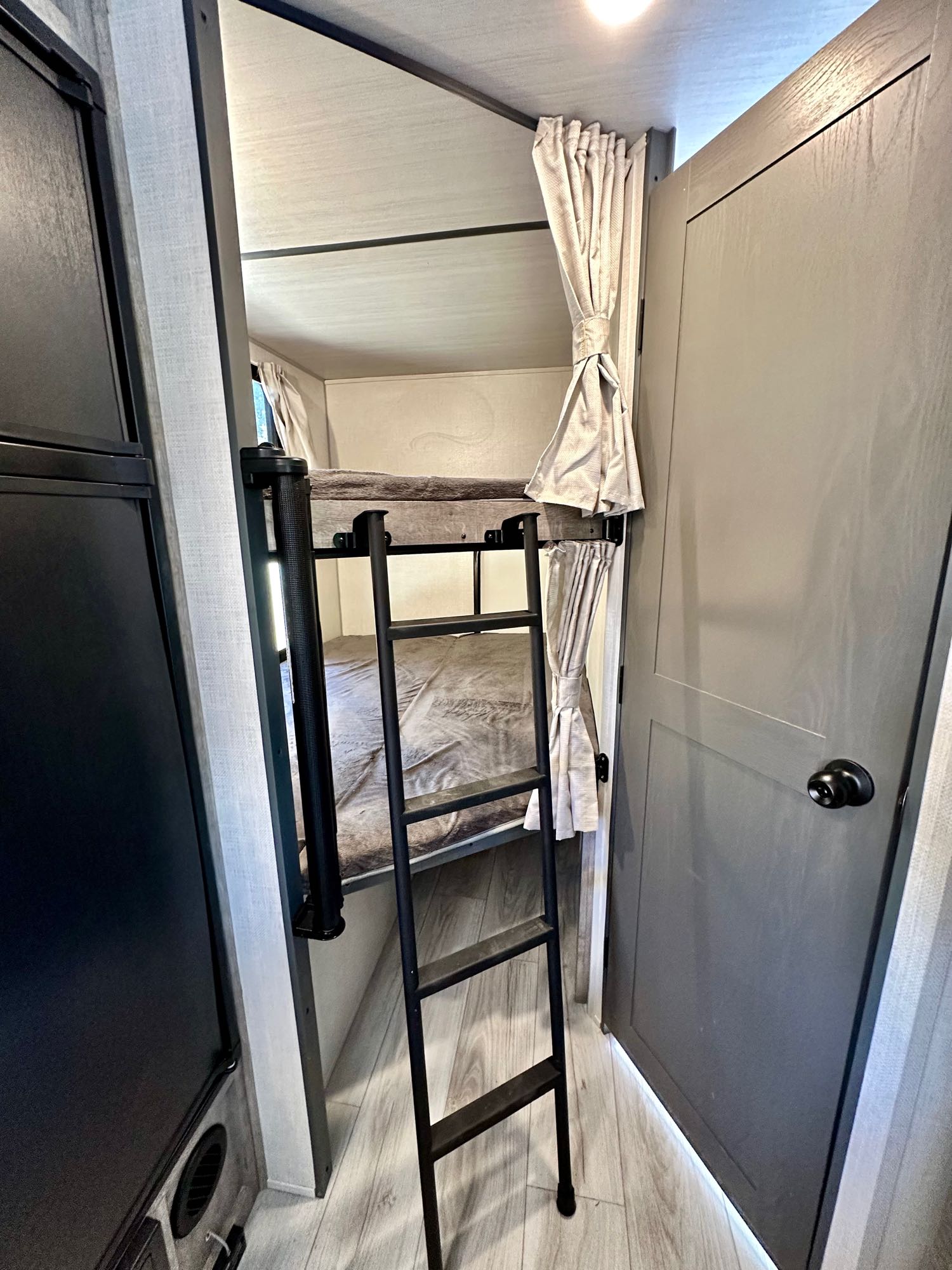This RV rental features cozy bunk beds with a ladder for easy access, and privacy curtains. Ideal compact sleeping.. Forest River Surveyor Legend 2023