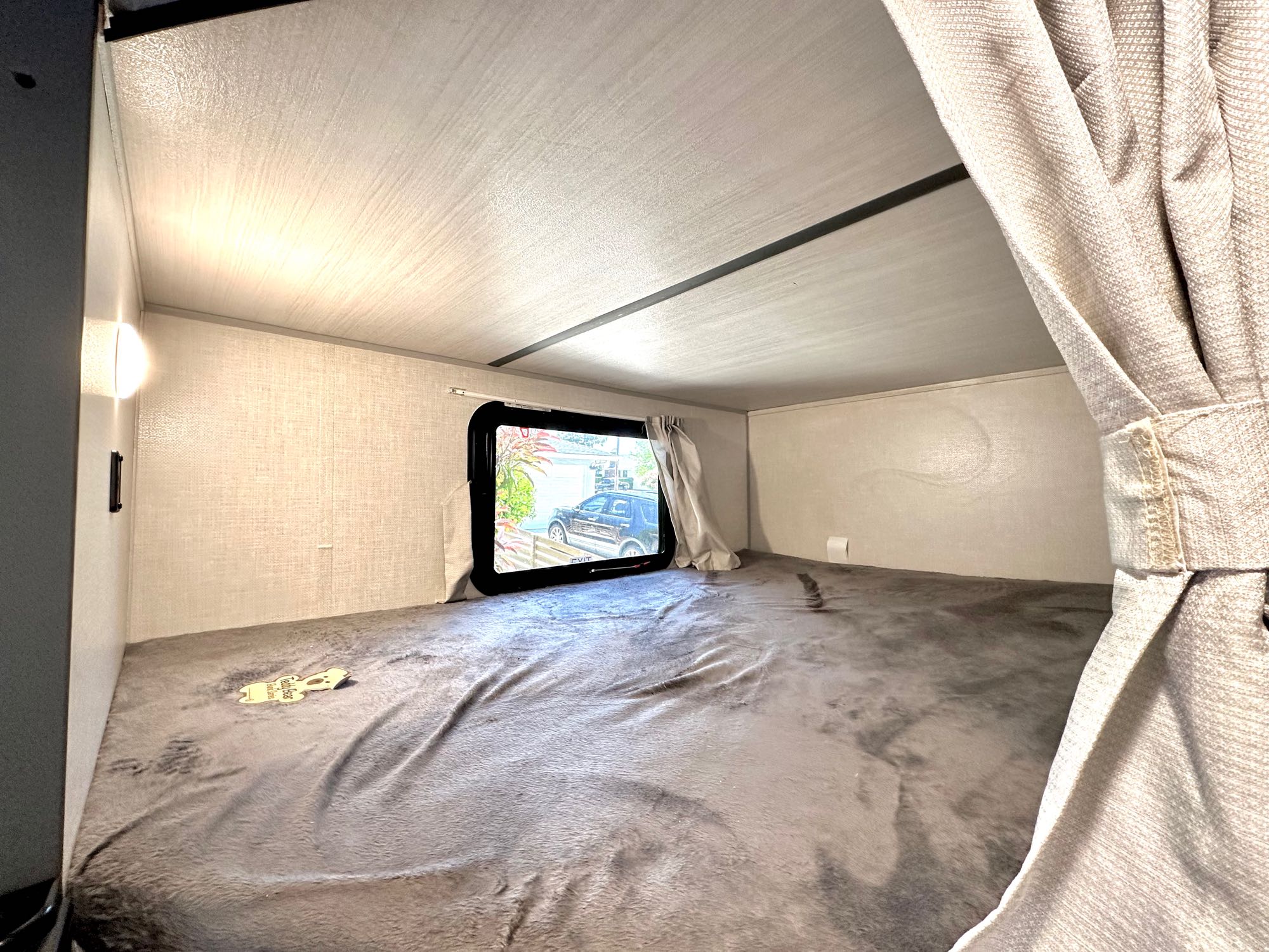 RV rental: A cozy, wide bunk bed with a soft grey blanket, window view,. Forest River Surveyor Legend 2023