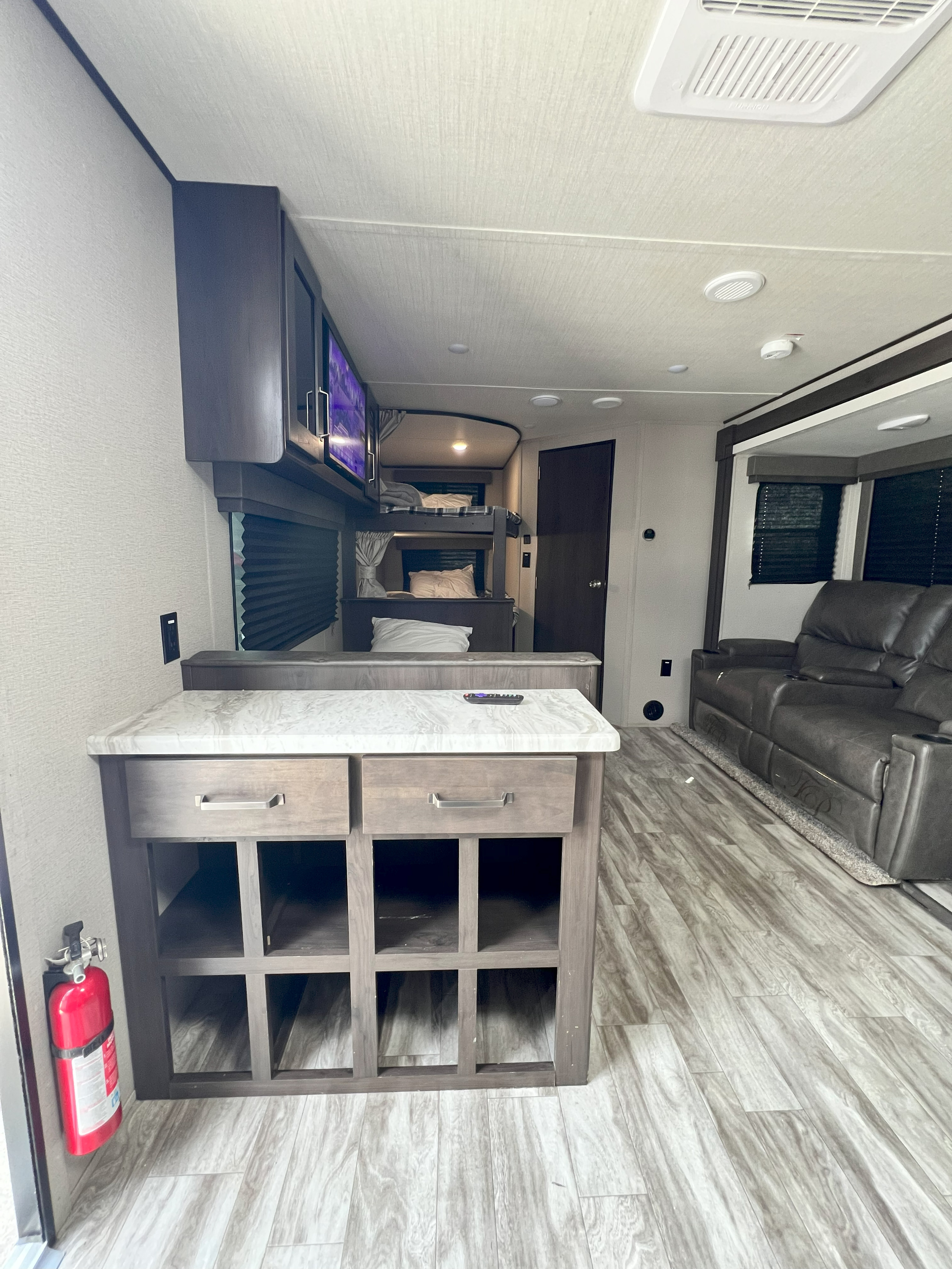 View inside a modern **RV rental**, featuring a kitchen island, bunk beds, and a comfy living area with recliners.. Grand Design 261BH 2021
