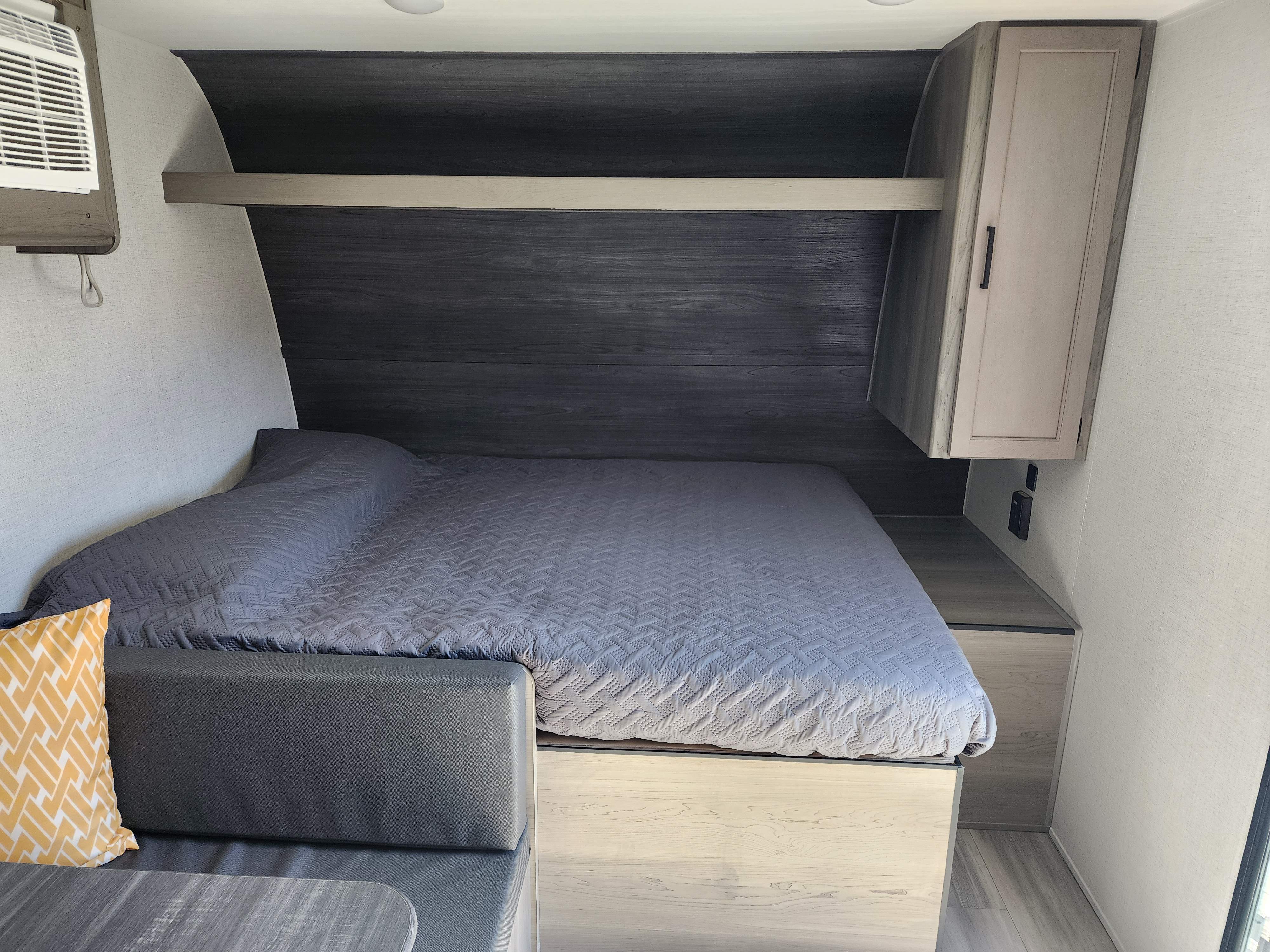 RV rental interior: A modern, compact bedroom featuring a grey quilted bed, wood-toned storage, and AC unit.. Keystone RV Hideout 175BH 2024