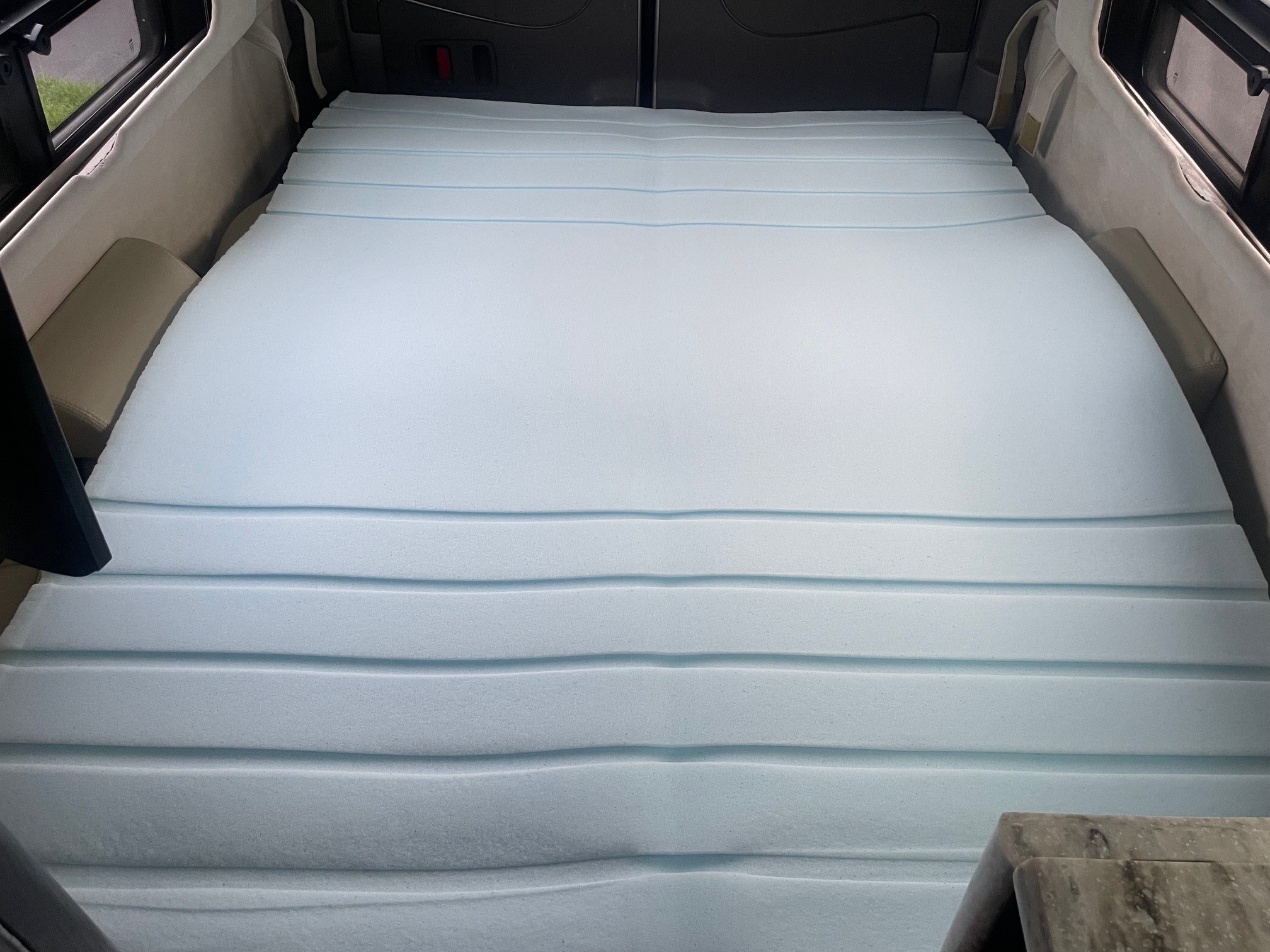 Light blue segmented foam mattress creating a comfortable bed inside an RV rental. Ideal for camper van sleeping.. Airstream Interstate 2014