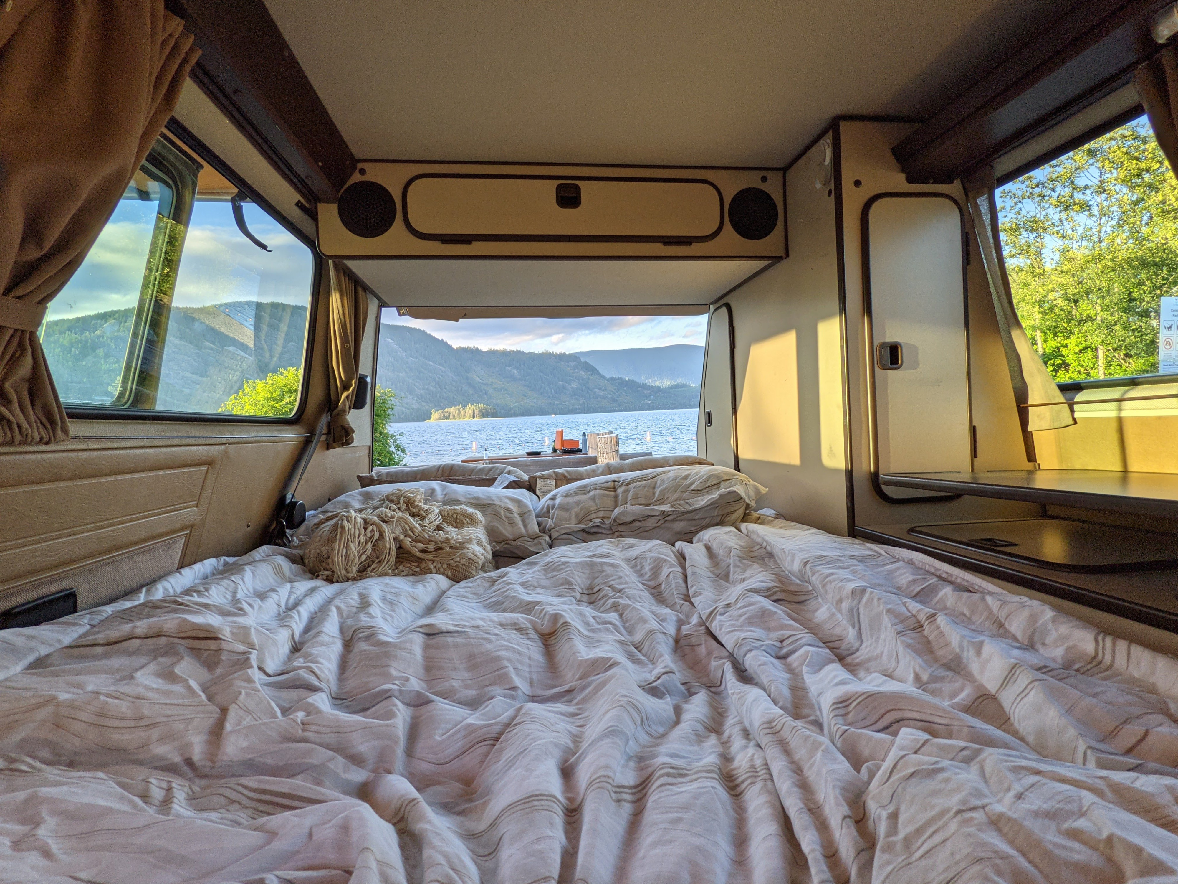 Cozy RV rental bed overlooks a stunning lake and mountain view, offering a serene escape.. Volkswagen Westfalia 1989