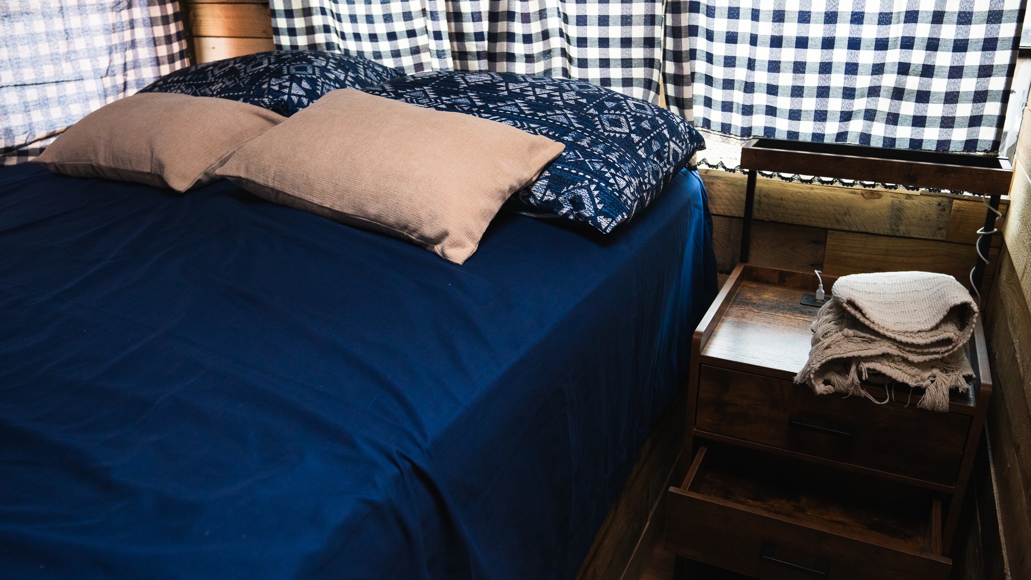 Inviting RV rental bedroom: blue bed, patterned pillows, and a nightstand with cozy throws.. Freightliner FS 65 2007