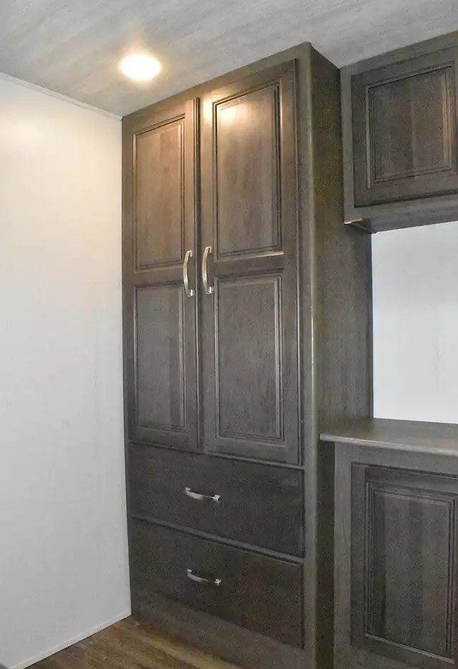 RV rental storage: Dark wood built-in cabinet with paneled doors and drawers. Ideal for compact RV interiors.. Keystone Cougar 2021