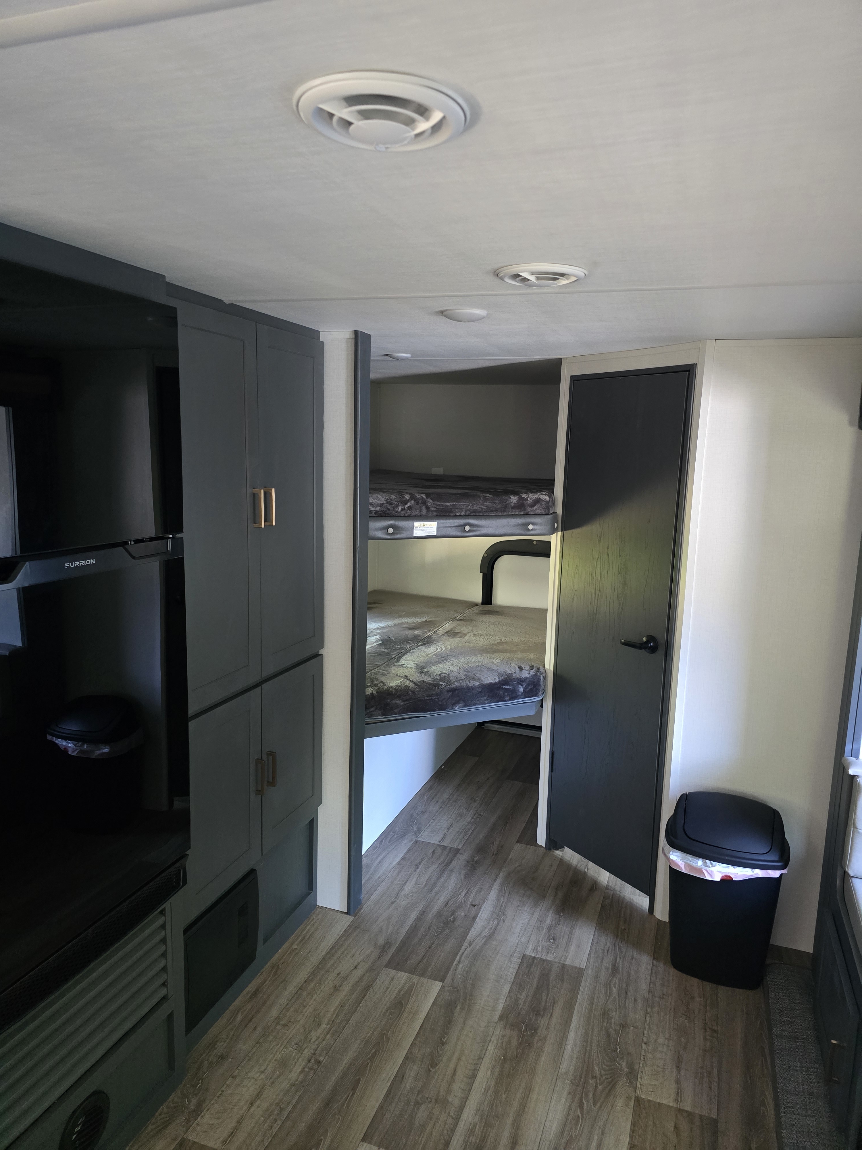 Modern RV rental interior: dark cabinets, bunk beds, and wood-look flooring.. Keystone RV Bullet Crossfire 2024