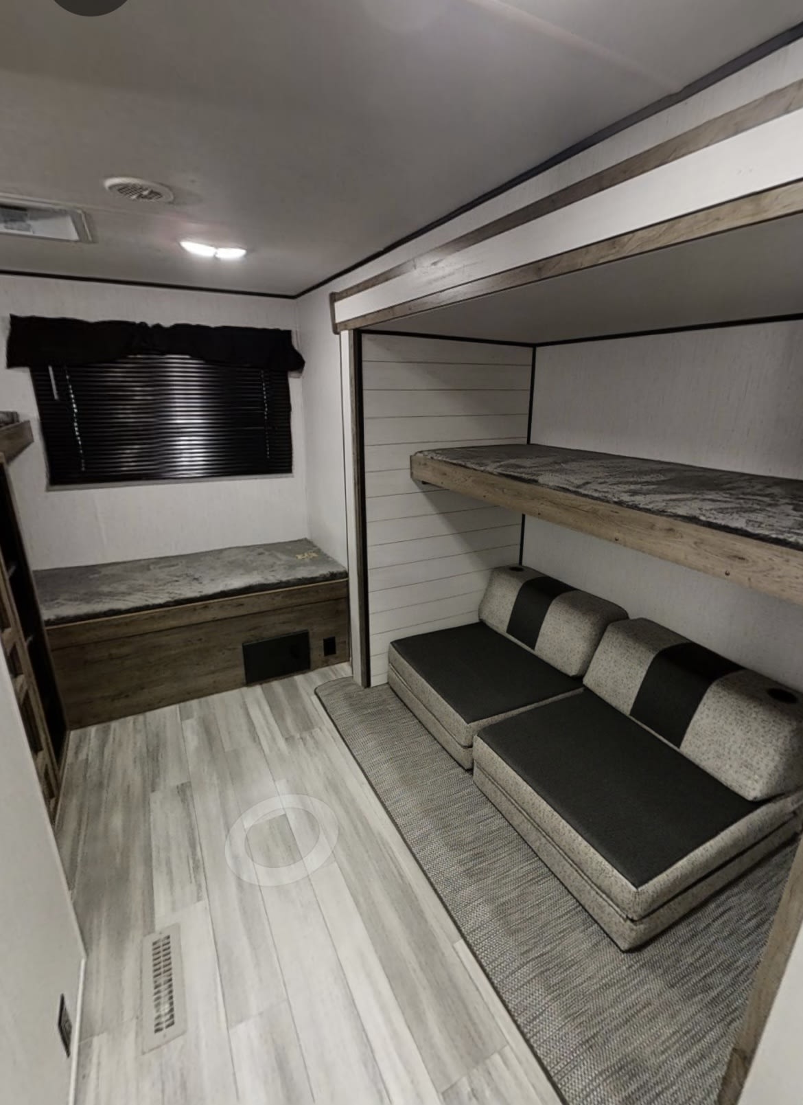 RV rental interior: light wood-look flooring leads to bunk beds, modular seating, and a storage bench with window.. Heartland RVs Pioneer 2020