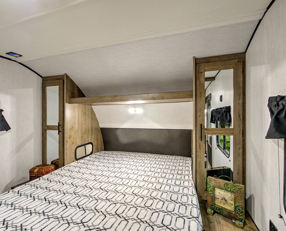Cozy RV rental bedroom with a comfortable bed, mirrored wardrobes, and overhead storage.. Heartland RVs Pioneer 2020