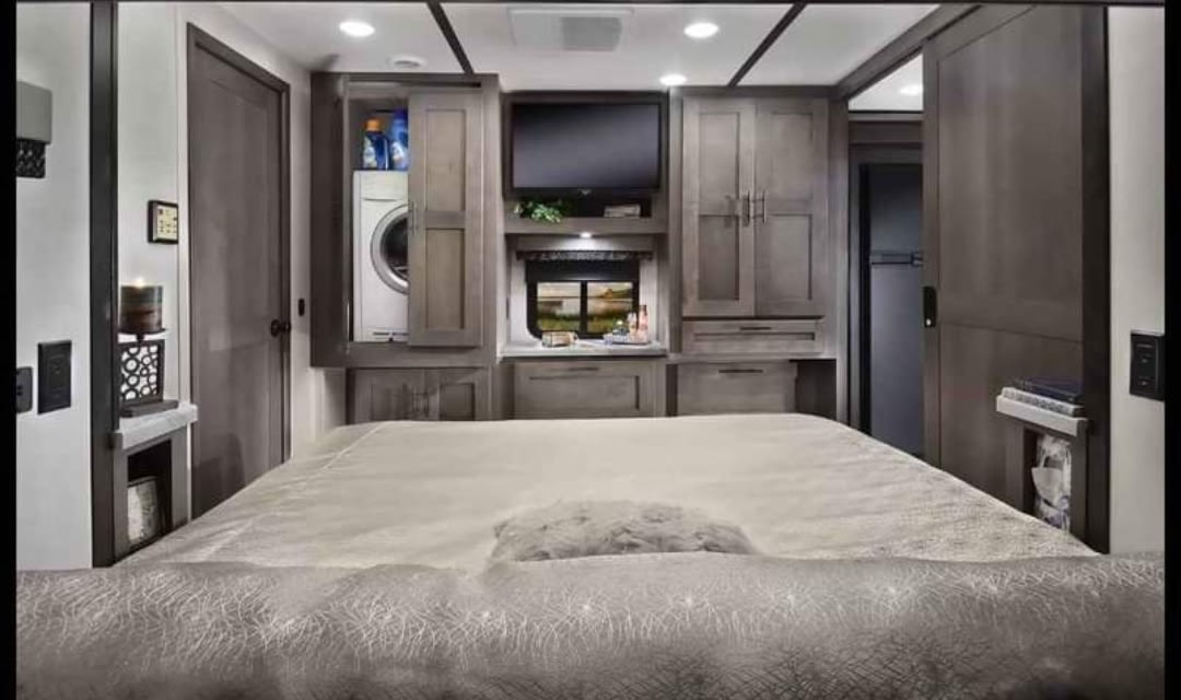Spacious RV rental bedroom featuring a large bed, built-in storage, TV, and a convenient washer/dryer combo.. FR3 FR3 Motorhome 2023