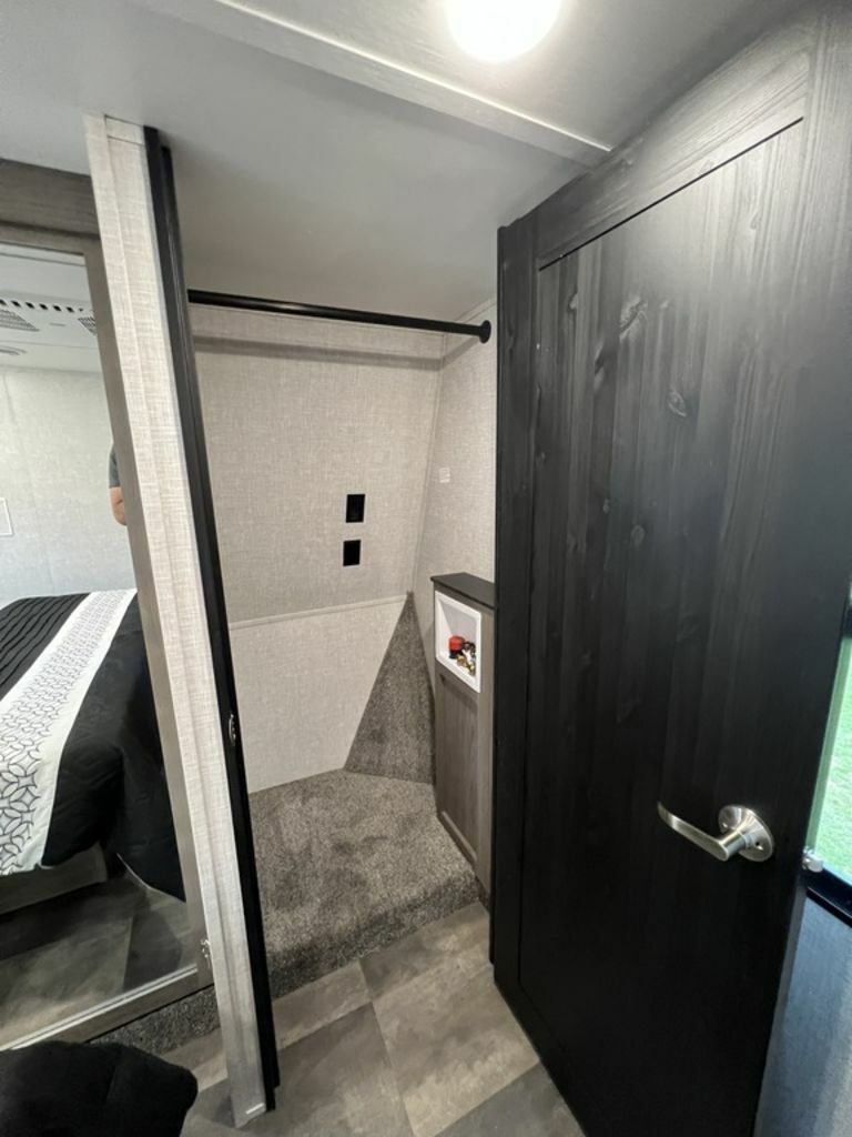 RV rental interior: Built-in closet, laundry hookups, and unique carpeted step. Functional layout with bed reflection & dark door.. Crossroads Cameo 2021