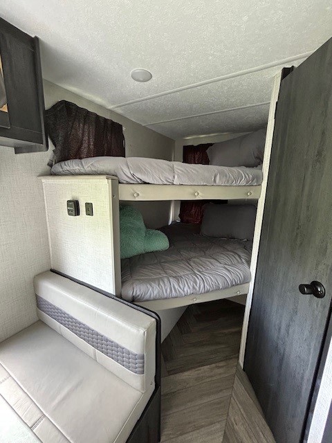 RV rental interior: cozy bunk beds with grey bedding and a dinette. Perfect for family adventures.. Forest River Ozark 2021
