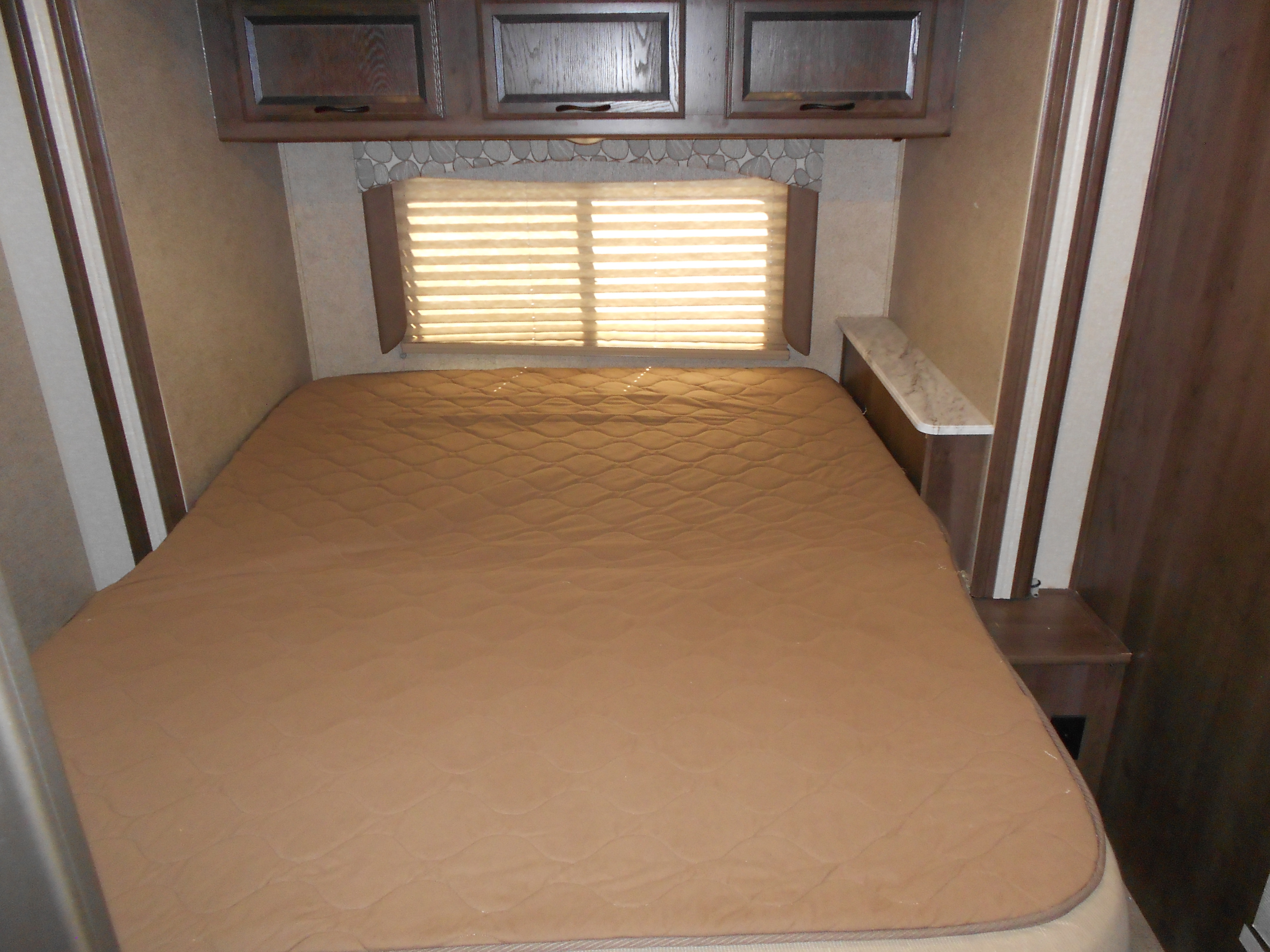 RV rental: Bedroom with a comfortable, quilted bed, overhead cabinets, and window with blinds.. Coachmen Freelander 2018