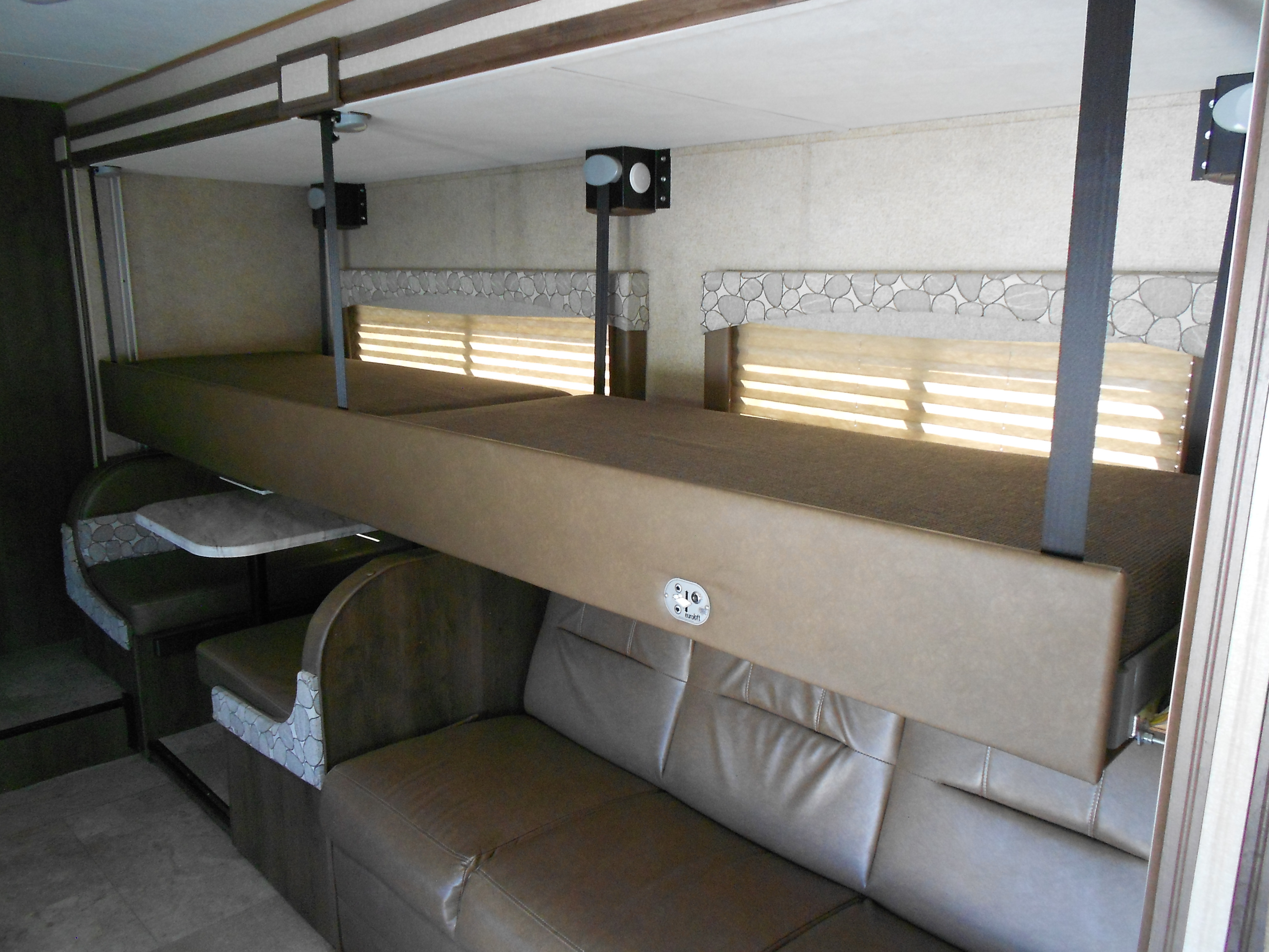 Inside an RV rental: a flexible sleeping setup with a EuroLoft bunk bed above a dinette and sofa.. Coachmen Freelander 2018