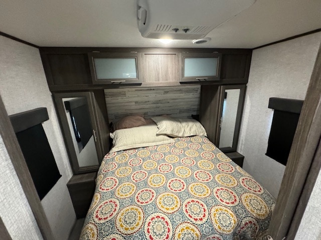 Inside a modern RV rental, this bedroom offers a cozy bed, smart overhead storage, and mirrored wardrobes for convenience.. Dutchmen Kodiak Ultra Lite 2021
